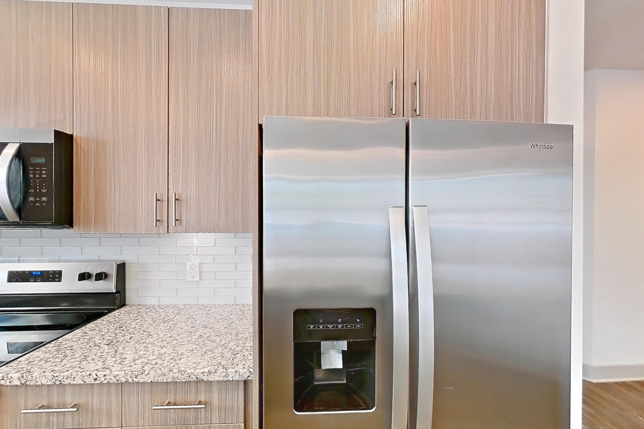 Kitchen with dark wood-finish flooring, dishwasher, electric range, light countertops, light stone countertops, oven/range, and stainless steel appliances, Apartment B2-102 at Lantower Grande Flats