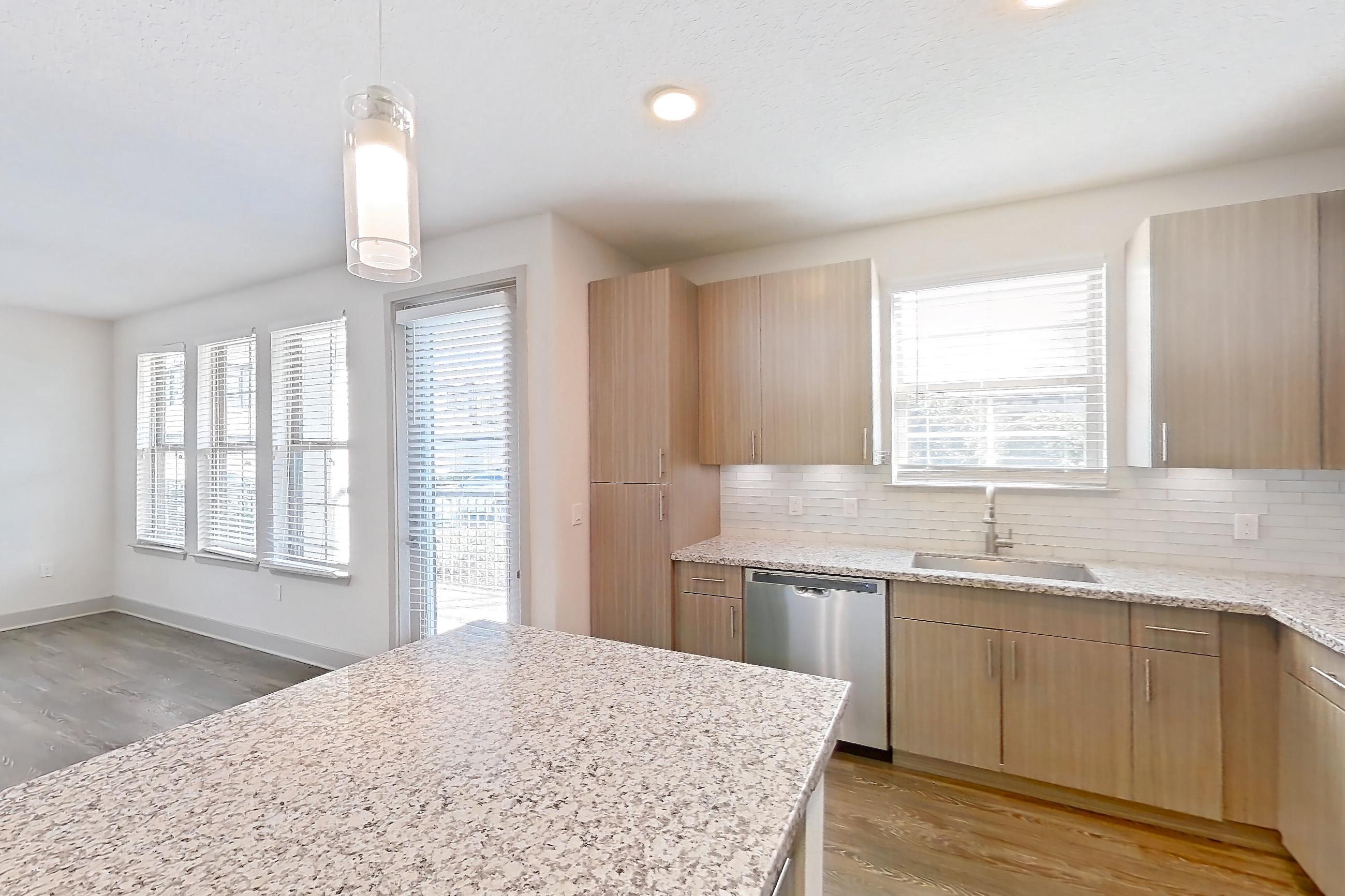Kitchen with dark wood-finish flooring, dishwasher, electric range, light countertops, light stone countertops, oven/range, and stainless steel appliances, Apartment B2-102 at Lantower Grande Flats