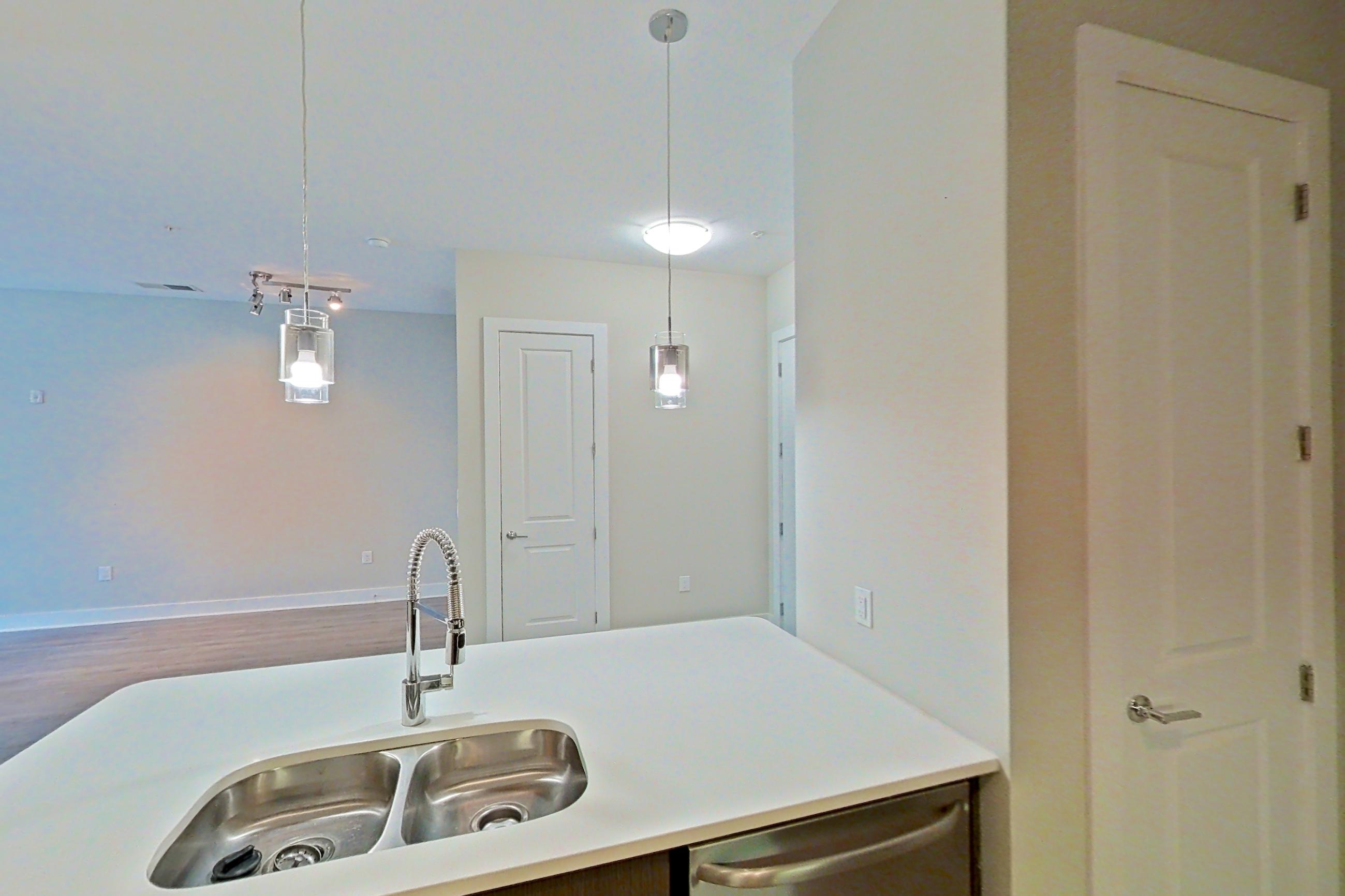 Kitchen with dishwasher, electric range, light countertops, light wood-finish flooring, microwave, oven/range, range hood, refrigerator, stainless steel appliances, and water & ice dispenser, Apartment 331 at BullHouse