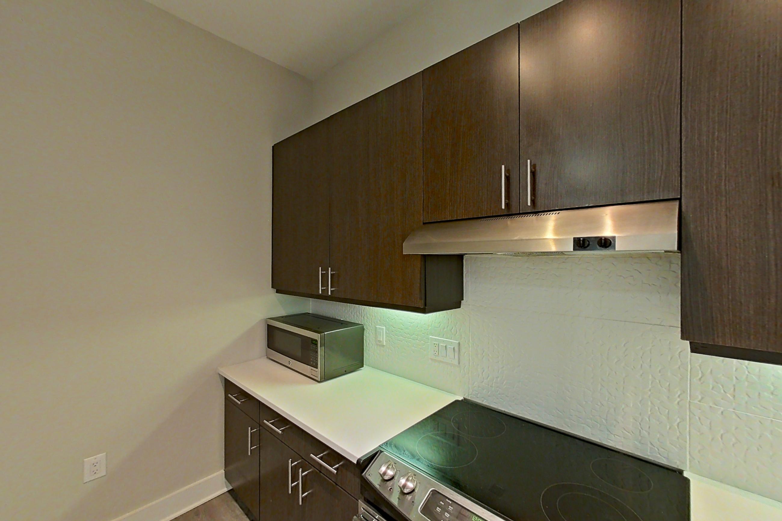 Kitchen with dishwasher, electric range, light countertops, light wood-finish flooring, microwave, oven/range, range hood, refrigerator, stainless steel appliances, and water & ice dispenser, Apartment 331 at BullHouse