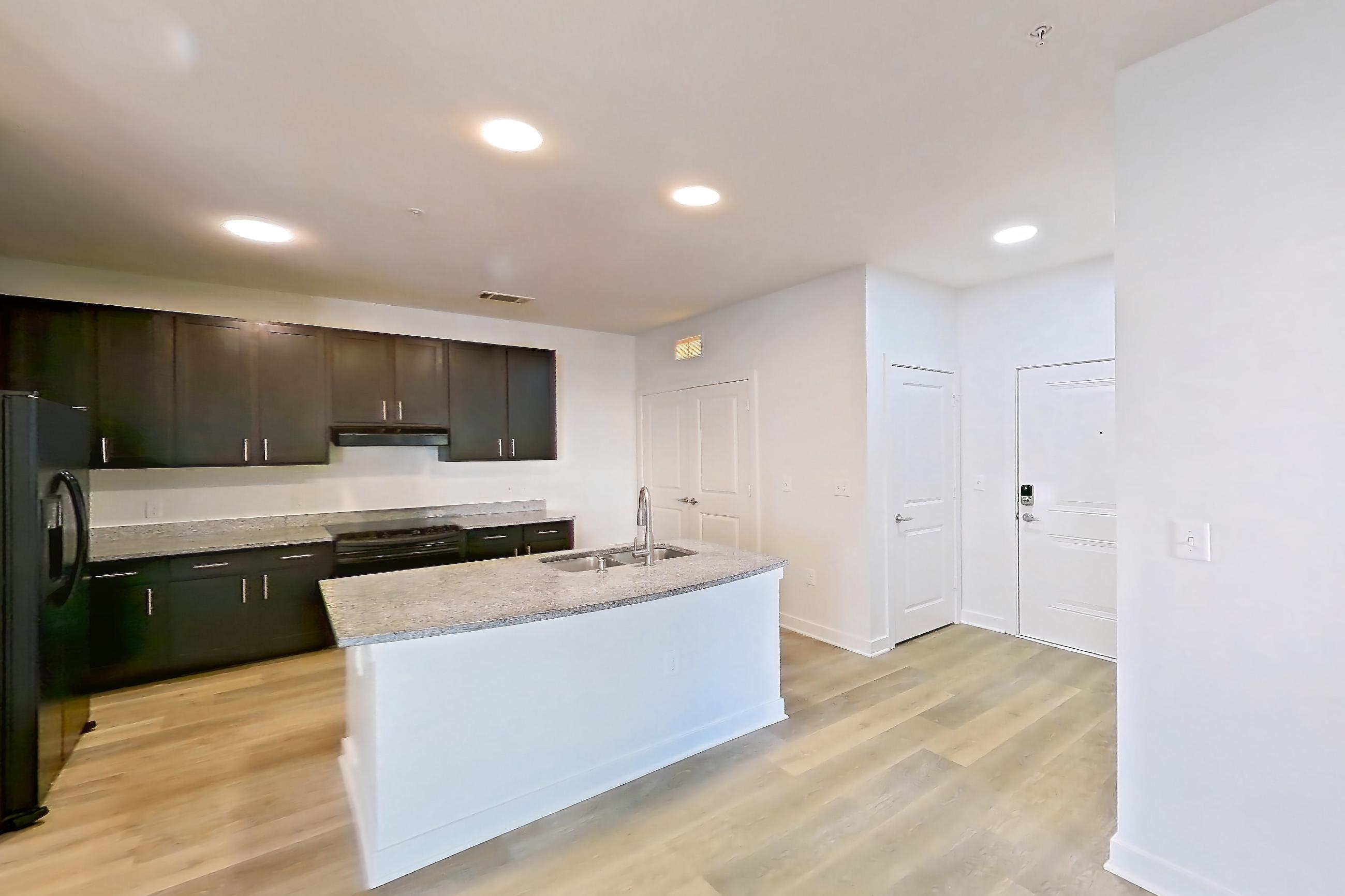 Dining room with black appliances, kitchen island, light stone countertops, light wood-finish flooring, oven/range, refrigerator, and stainless steel appliances, Apartment 304 at Realm at Patterson Place