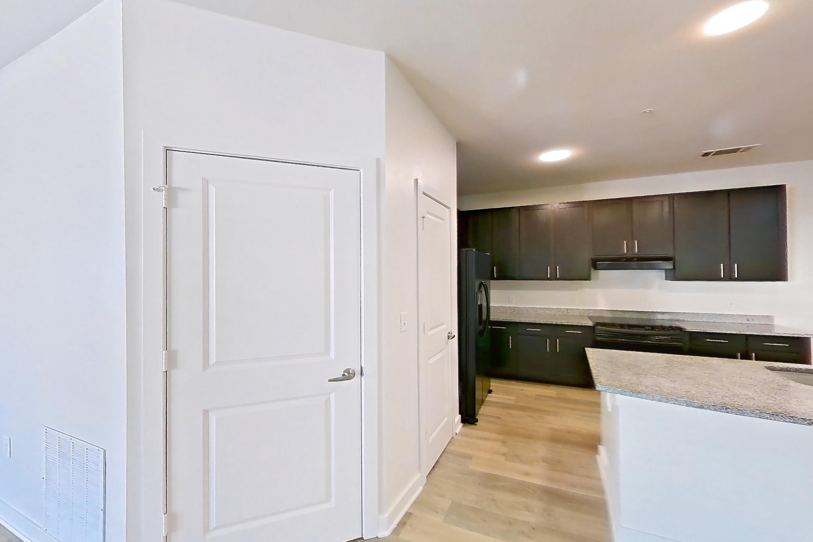 Dining room with black appliances, kitchen island, light stone countertops, light wood-finish flooring, oven/range, refrigerator, and stainless steel appliances, Apartment 304 at Realm at Patterson Place