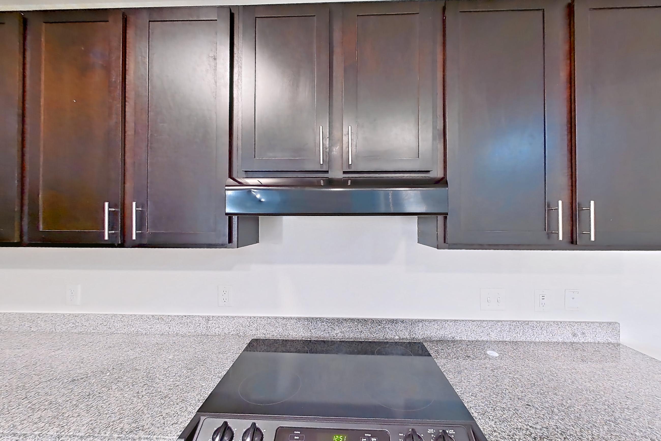 Kitchen with black appliances, dishwasher, electric range, light countertops, light stone countertops, light wood-finish flooring, oven/range, refrigerator, and water & ice dispenser, Apartment 304 at Realm at Patterson Place