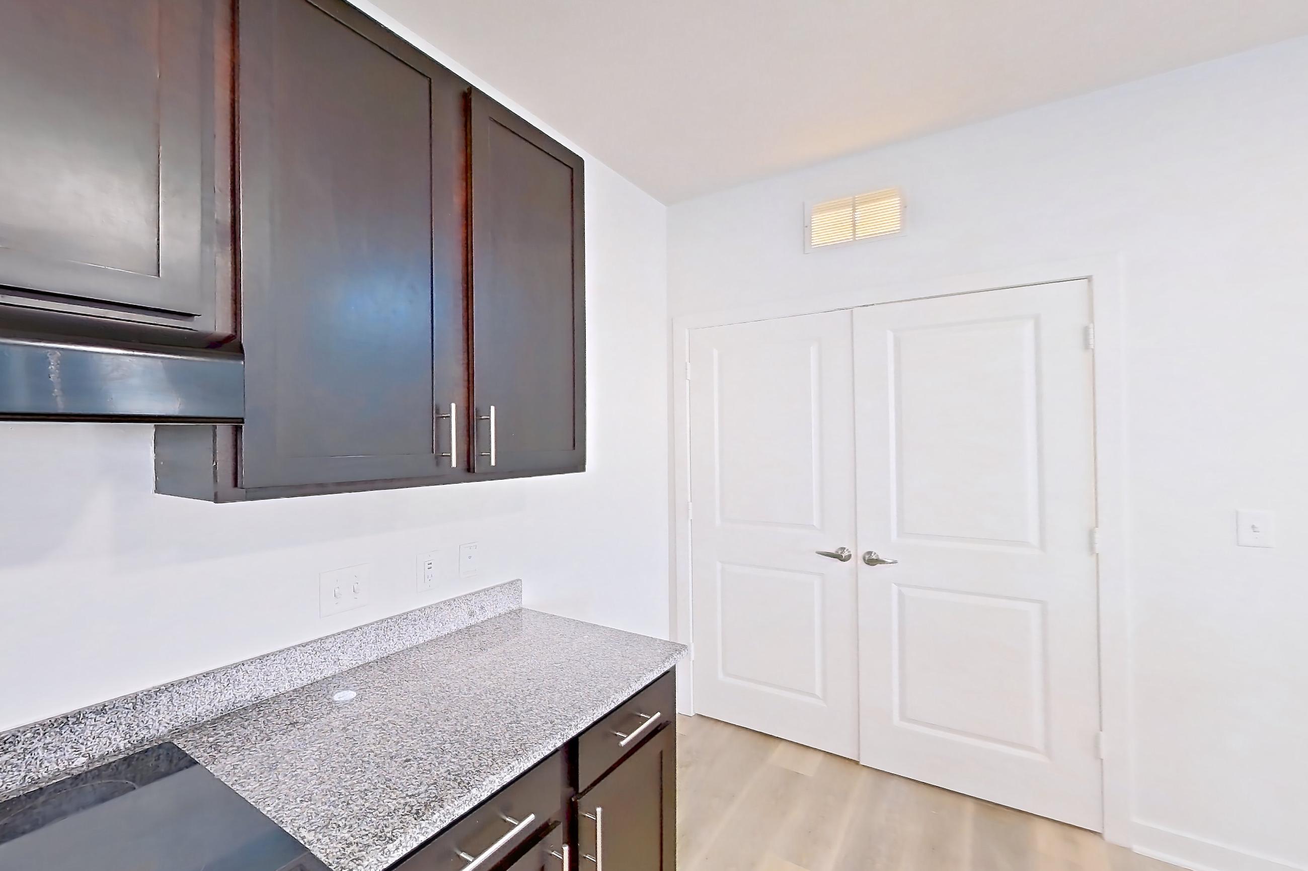 Kitchen with black appliances, dishwasher, electric range, light countertops, light stone countertops, light wood-finish flooring, oven/range, refrigerator, and water & ice dispenser, Apartment 304 at Realm at Patterson Place