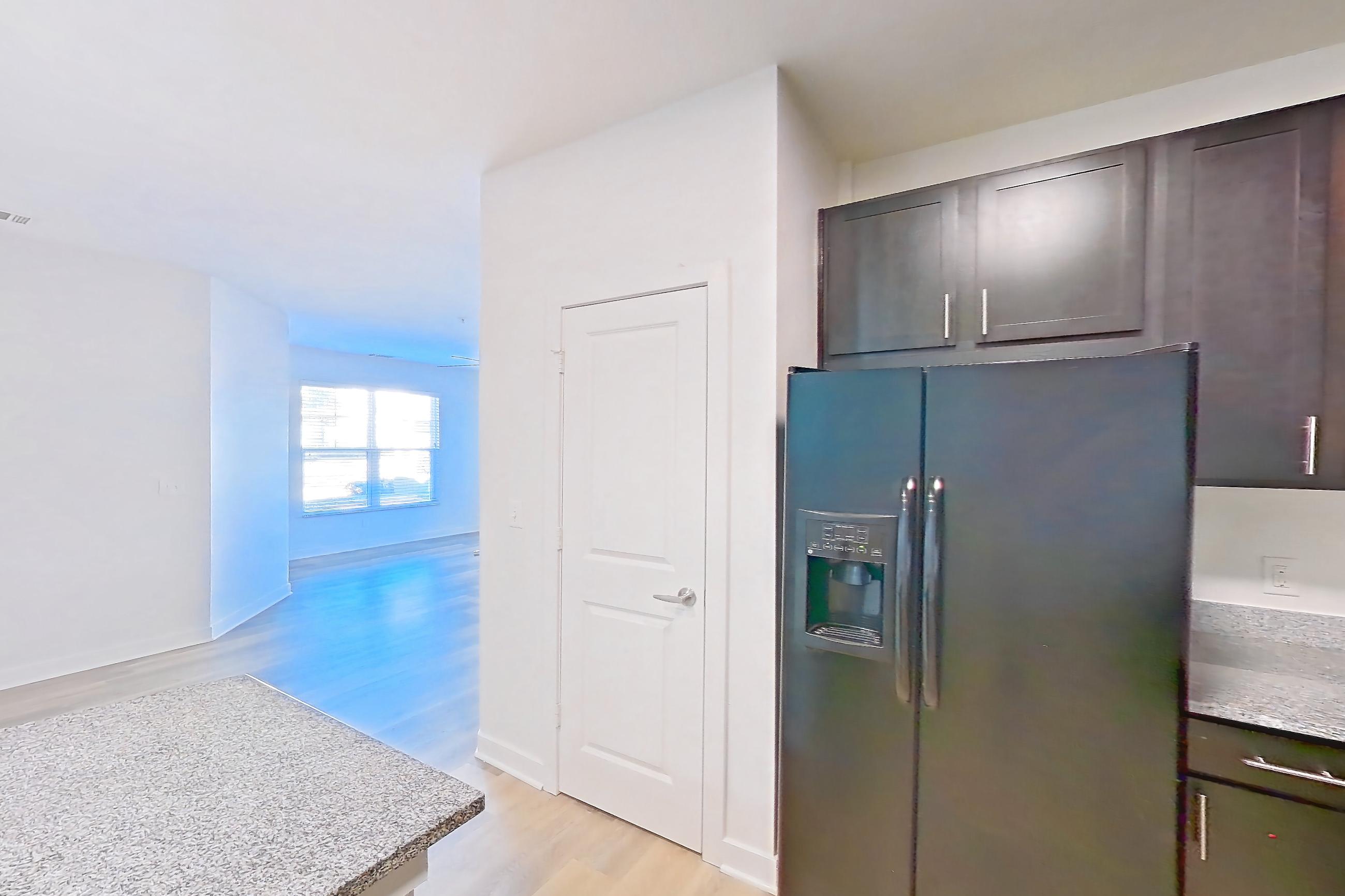 Kitchen with black appliances, dishwasher, electric range, light countertops, light stone countertops, light wood-finish flooring, oven/range, refrigerator, and water & ice dispenser, Apartment 304 at Realm at Patterson Place