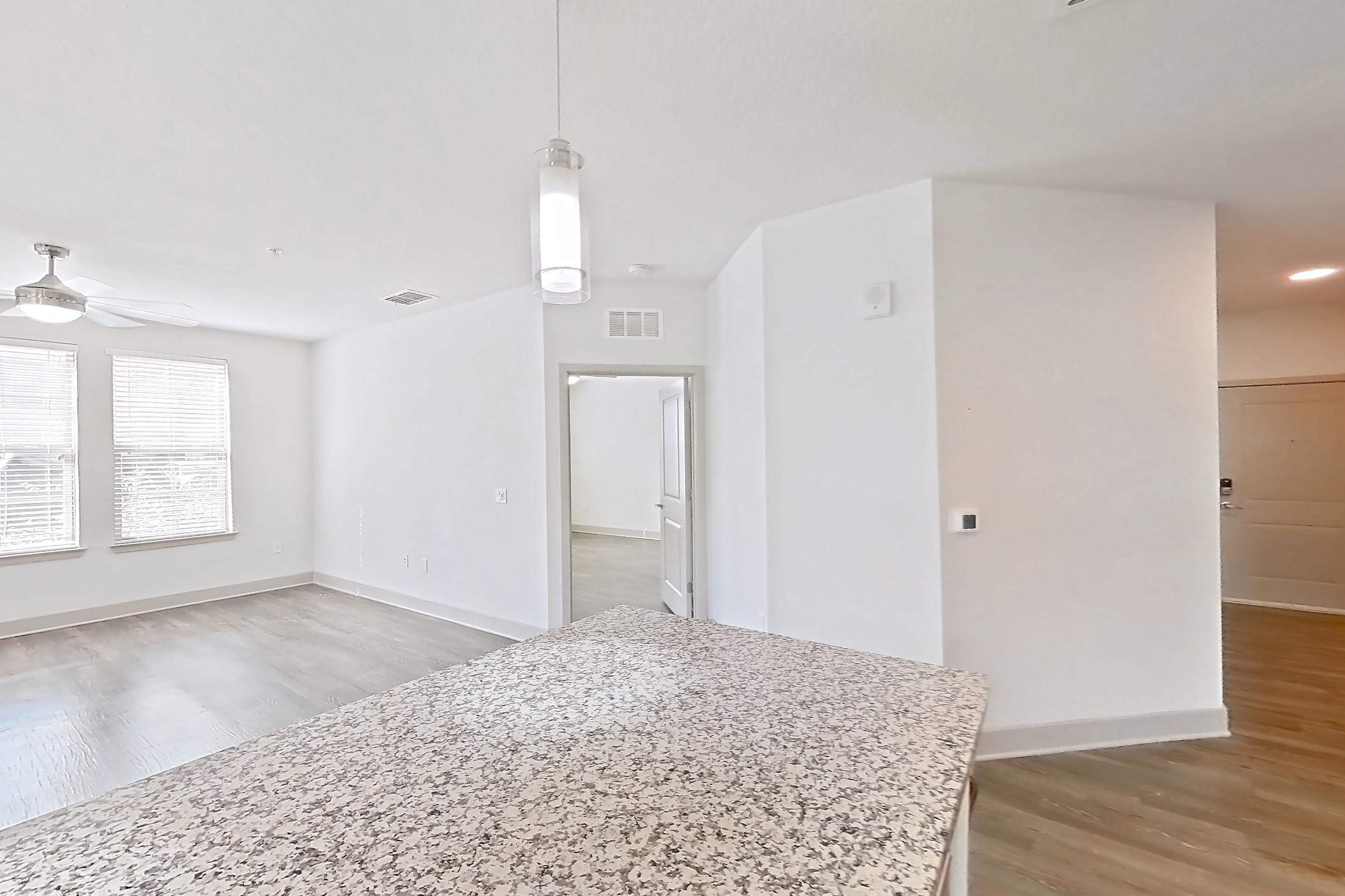 Kitchen with dark wood-finish flooring, dishwasher, electric range, light stone countertops, oven/range, refrigerator, and stainless steel appliances, Apartment B2-112 at Lantower Grande Flats