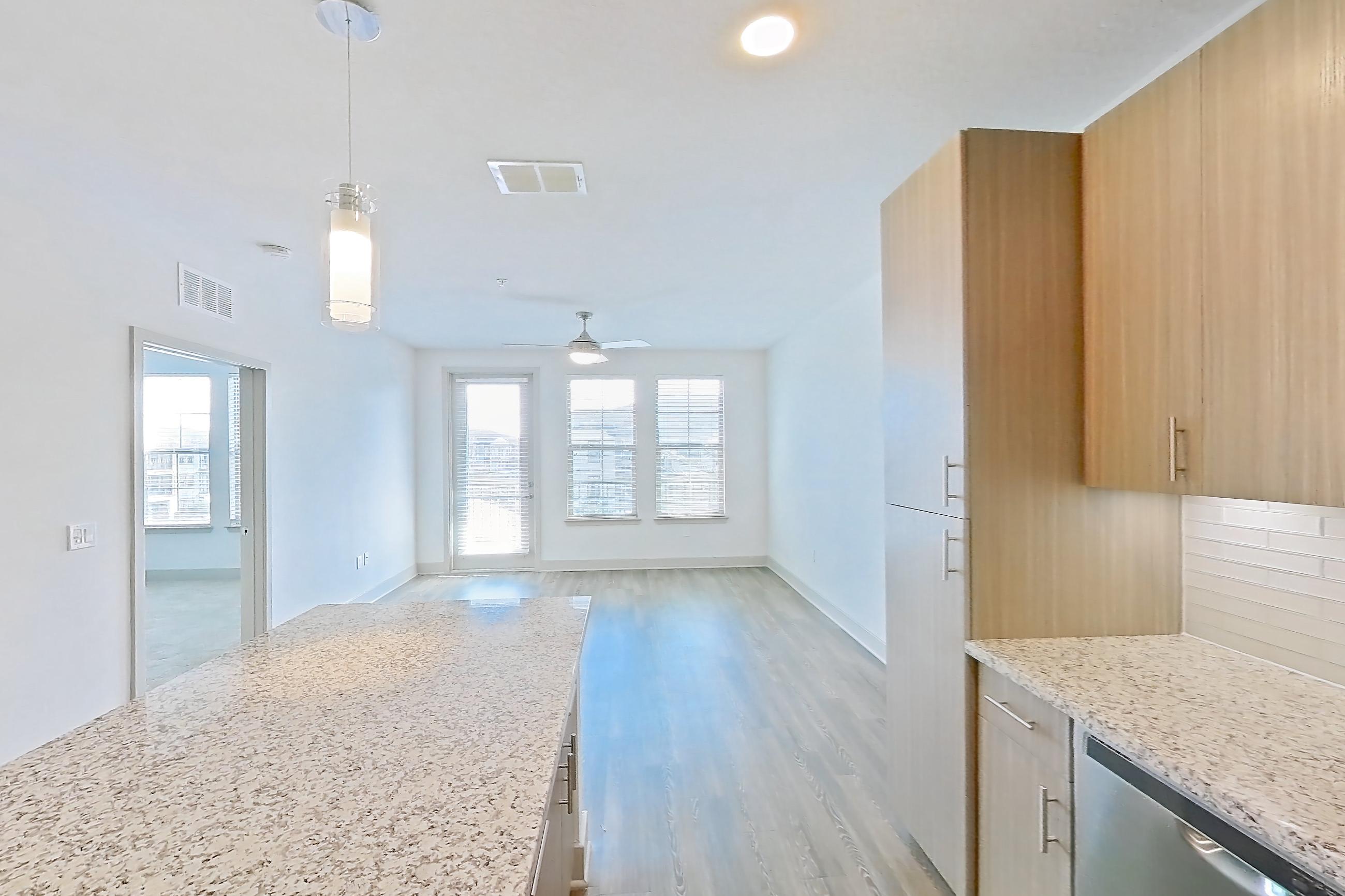 Kitchen with dark wood-finish flooring, dishwasher, electric range, light countertops, light stone countertops, light wood-finish flooring, microwave, oven/range, refrigerator, stainless steel appliances, and water & ice dispenser, Apartment B2-304 at Lantower Grande Flats