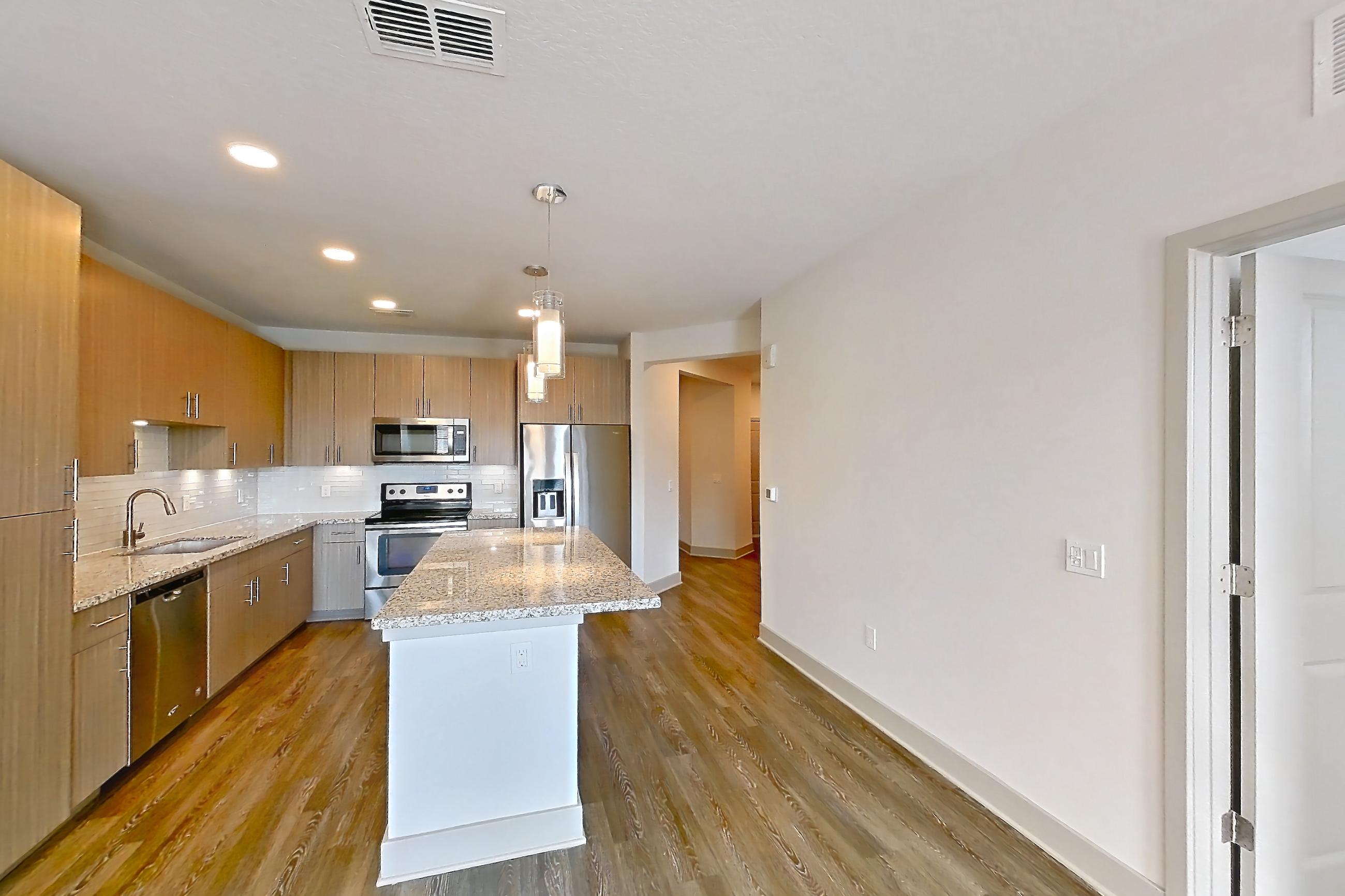 Living room with dark wood-finish flooring, electric range, light stone countertops, oven/range, refrigerator, smart refrigerator, stainless steel appliances, and water & ice dispenser, Apartment B2-304 at Lantower Grande Flats