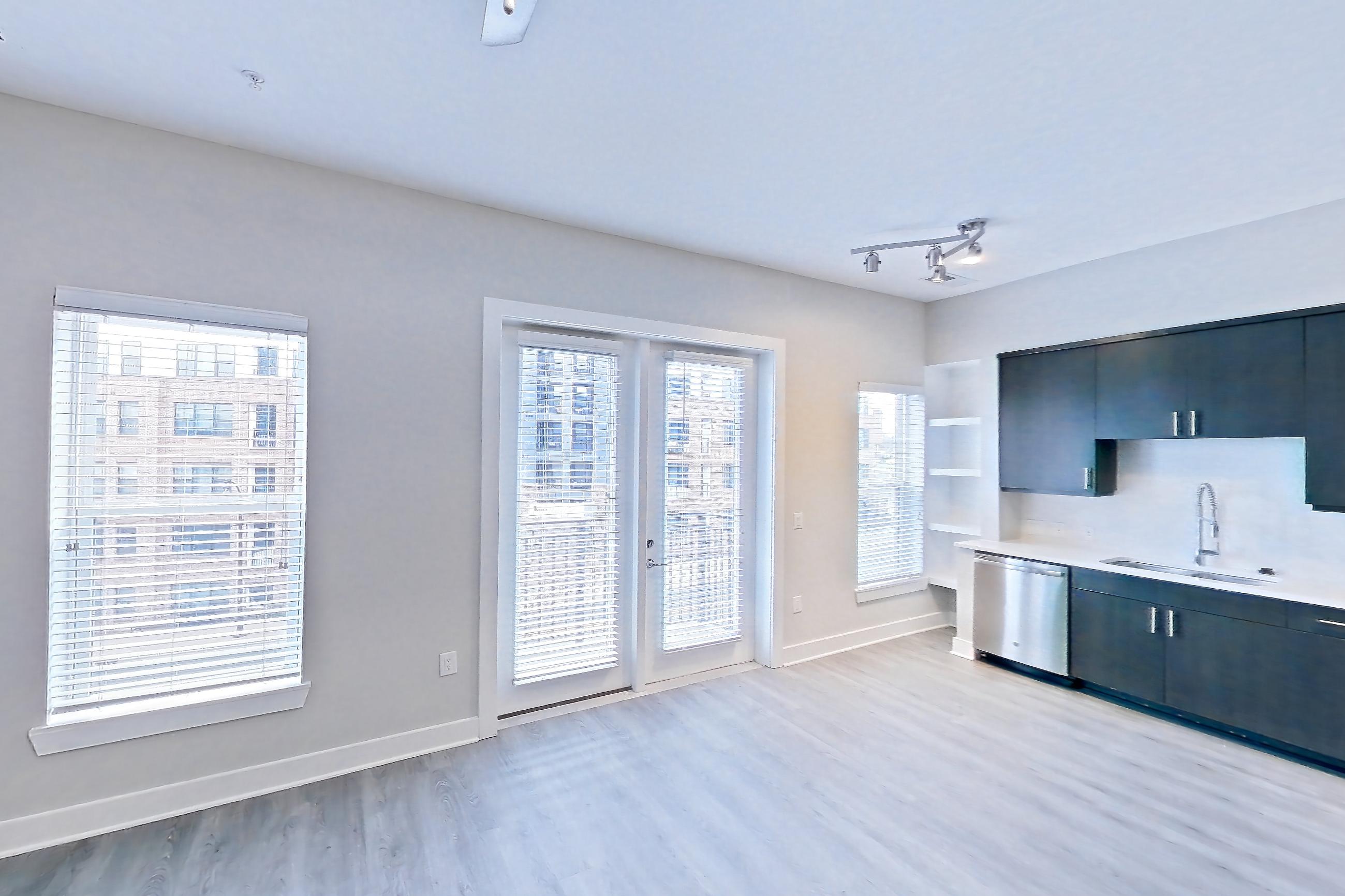 Living room with dark wood-finish flooring, dishwasher, electric range, light countertops, light vinyl flooring, light wood-finish flooring, microwave, oven/range, refrigerator, and stainless steel appliances, Apartment 415 at BullHouse