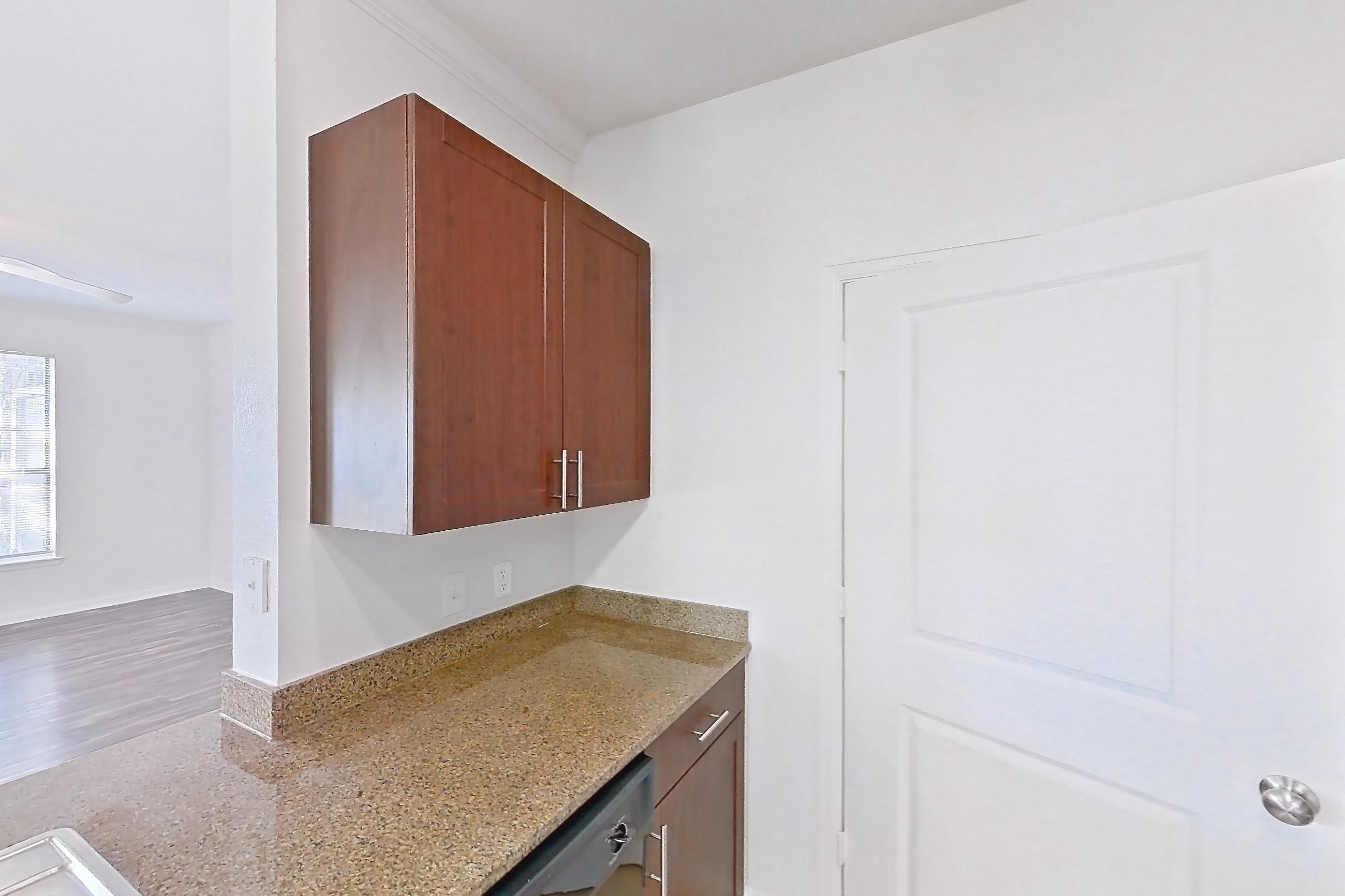 Kitchen with black appliances, dishwasher, electric range, light stone countertops, light tile flooring, light wood-finish flooring, microwave, oven/range, refrigerator, and stainless steel appliances, Apartment 811 at The Cortona