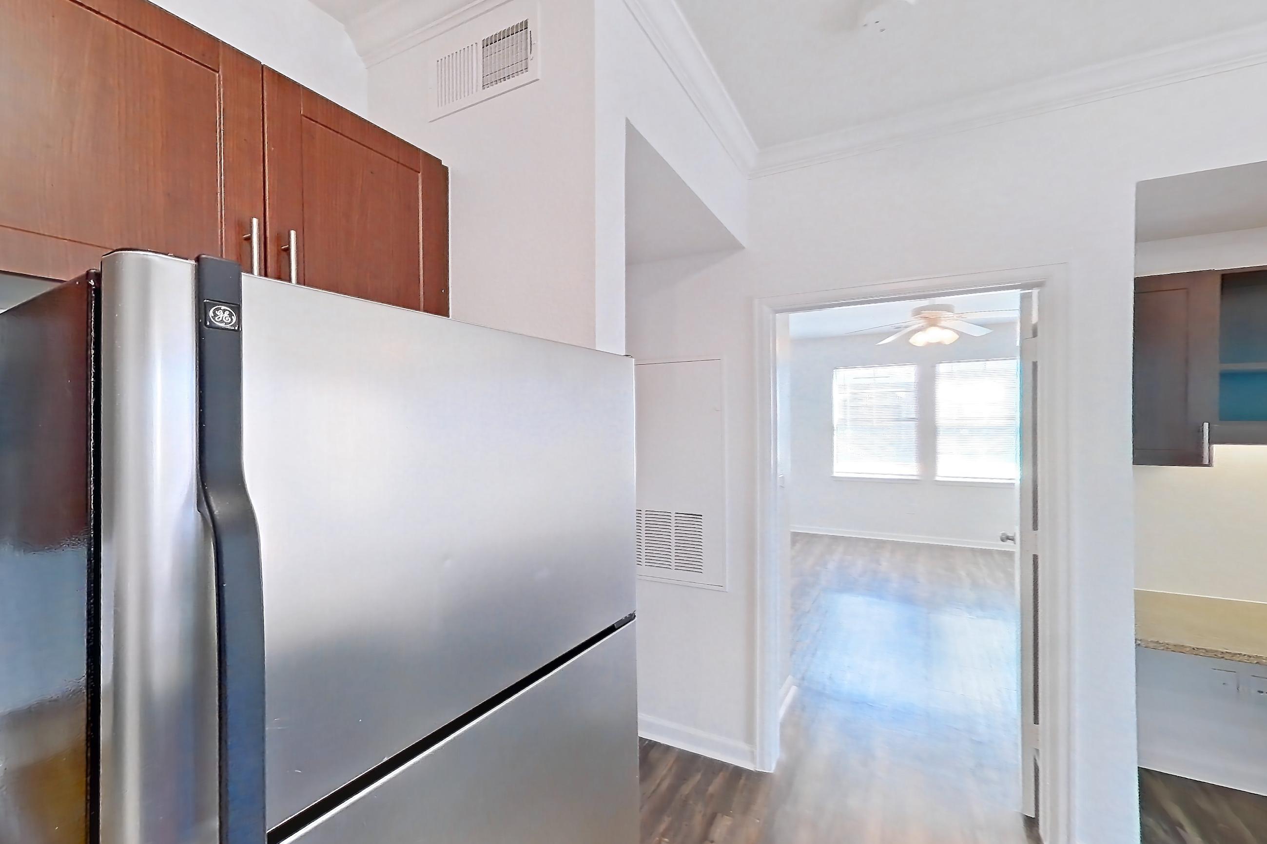 Kitchen with black appliances, dishwasher, electric range, light stone countertops, light tile flooring, light wood-finish flooring, microwave, oven/range, refrigerator, and stainless steel appliances, Apartment 811 at The Cortona