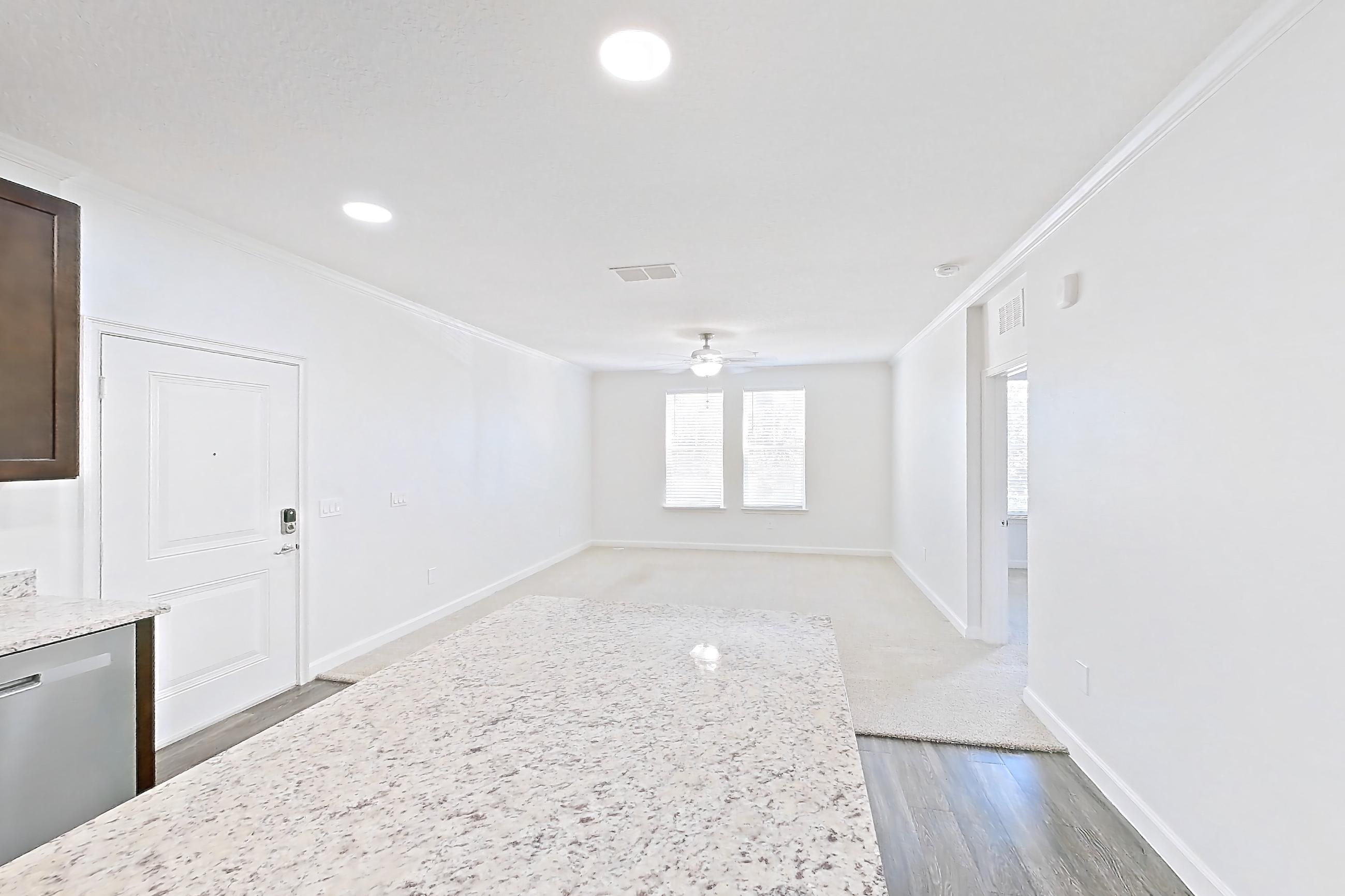 Kitchen with dark wood-finish flooring, dishwasher, electric range, light countertops, light stone countertops, microwave, oven/range, and stainless steel appliances, Apartment 6028 at Lantower Grande Pines