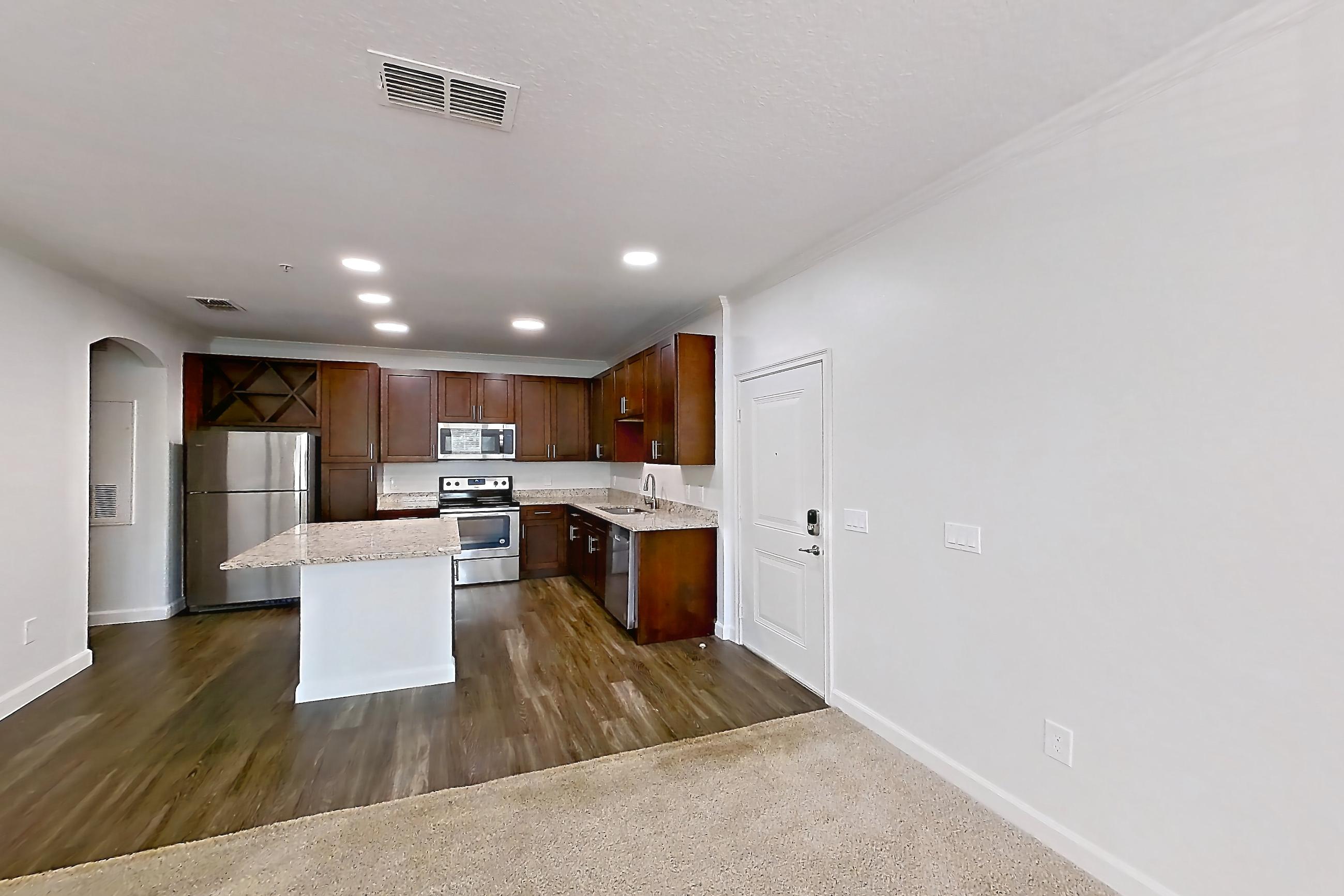 Living room with dark carpet, dishwasher, electric range, light stone countertops, oven/range, refrigerator, and stainless steel appliances, Apartment 6028 at Lantower Grande Pines