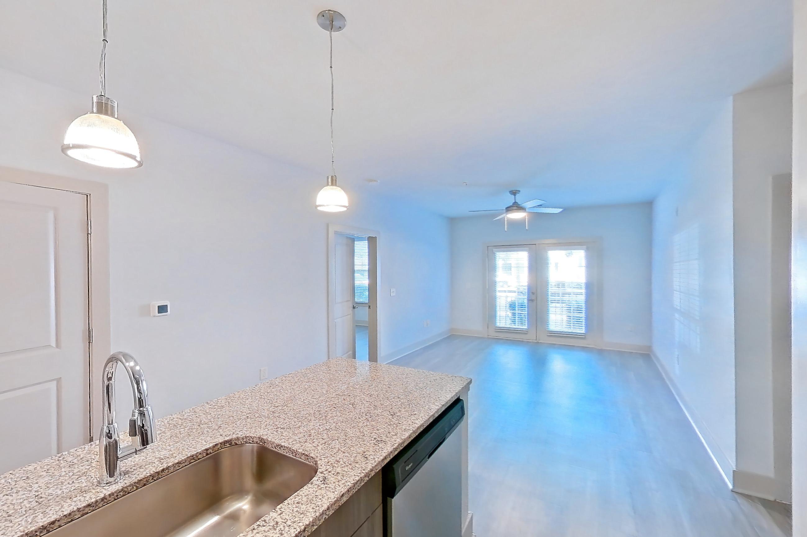Kitchen with dishwasher, electric range, light countertops, light stone countertops, light wood-finish flooring, microwave, oven/range, refrigerator, stainless steel appliances, and water & ice dispenser, Apartment 11108 at Lantower Waverly