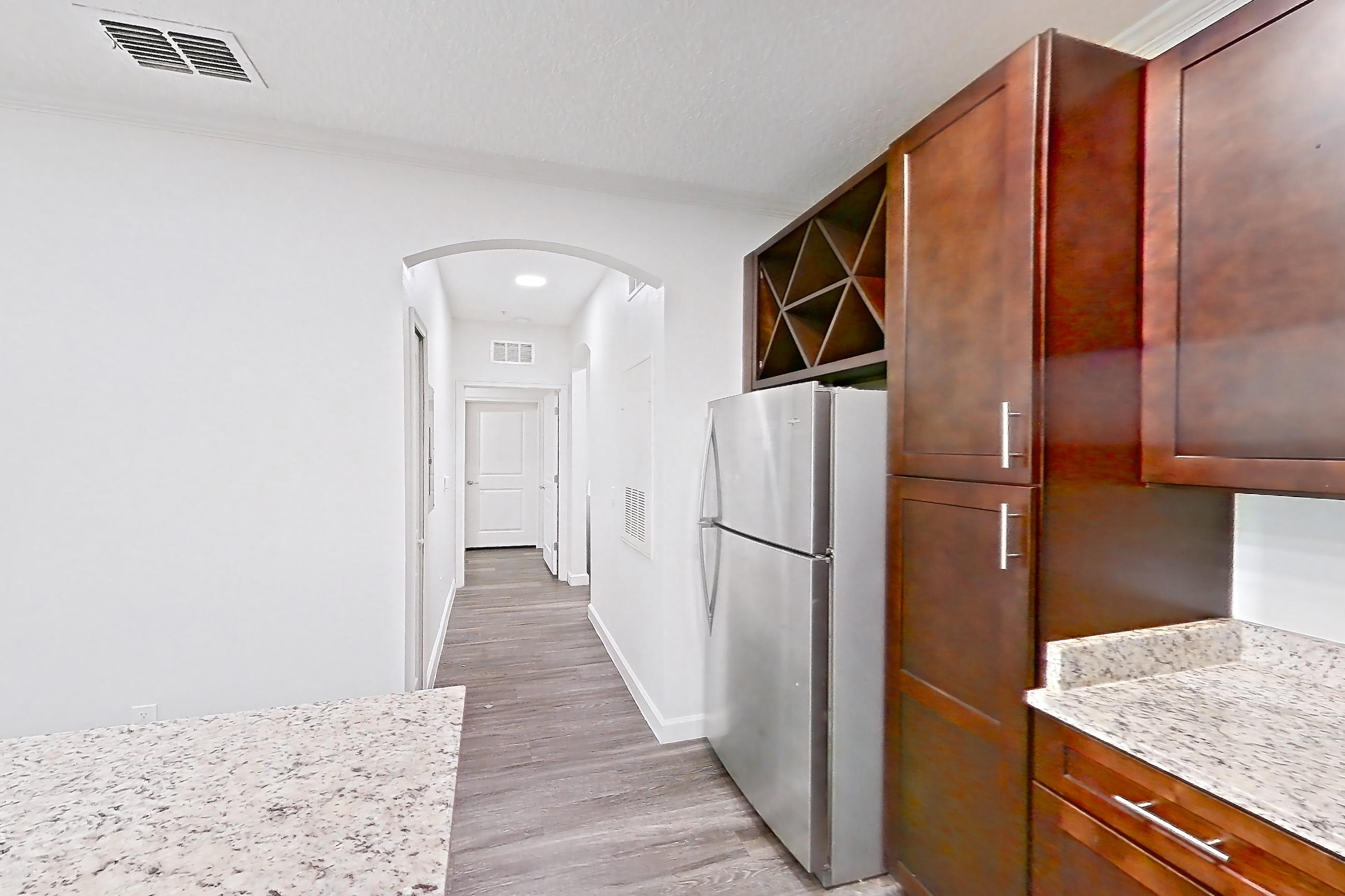 Kitchen with dishwasher, electric range, light stone countertops, light wood-finish flooring, microwave, oven/range, refrigerator, and stainless steel appliances, Apartment 5013 at Lantower Grande Pines