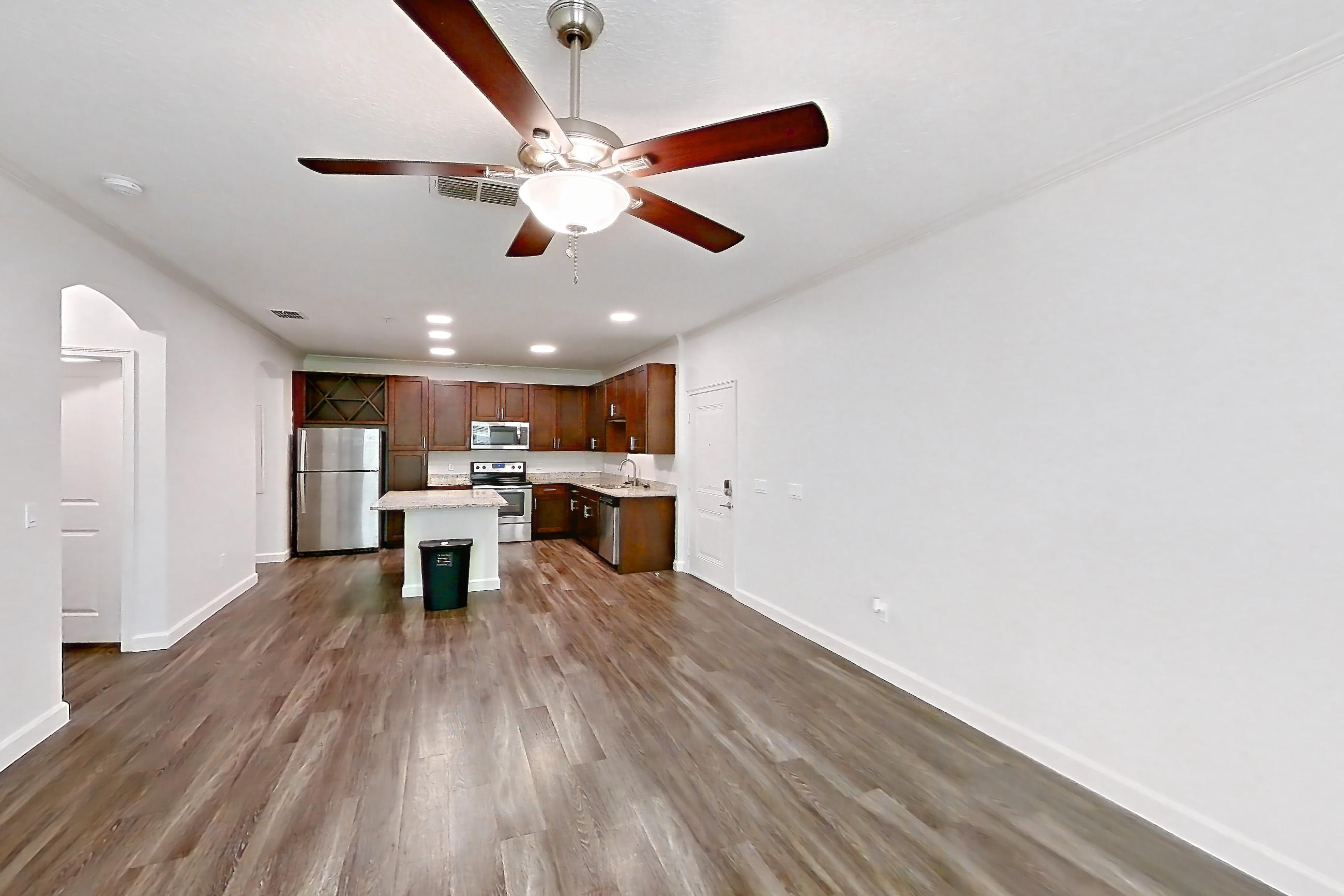 Living room with dark wood-finish flooring, electric range, light stone countertops, oven/range, and stainless steel appliances, Apartment 5013 at Lantower Grande Pines