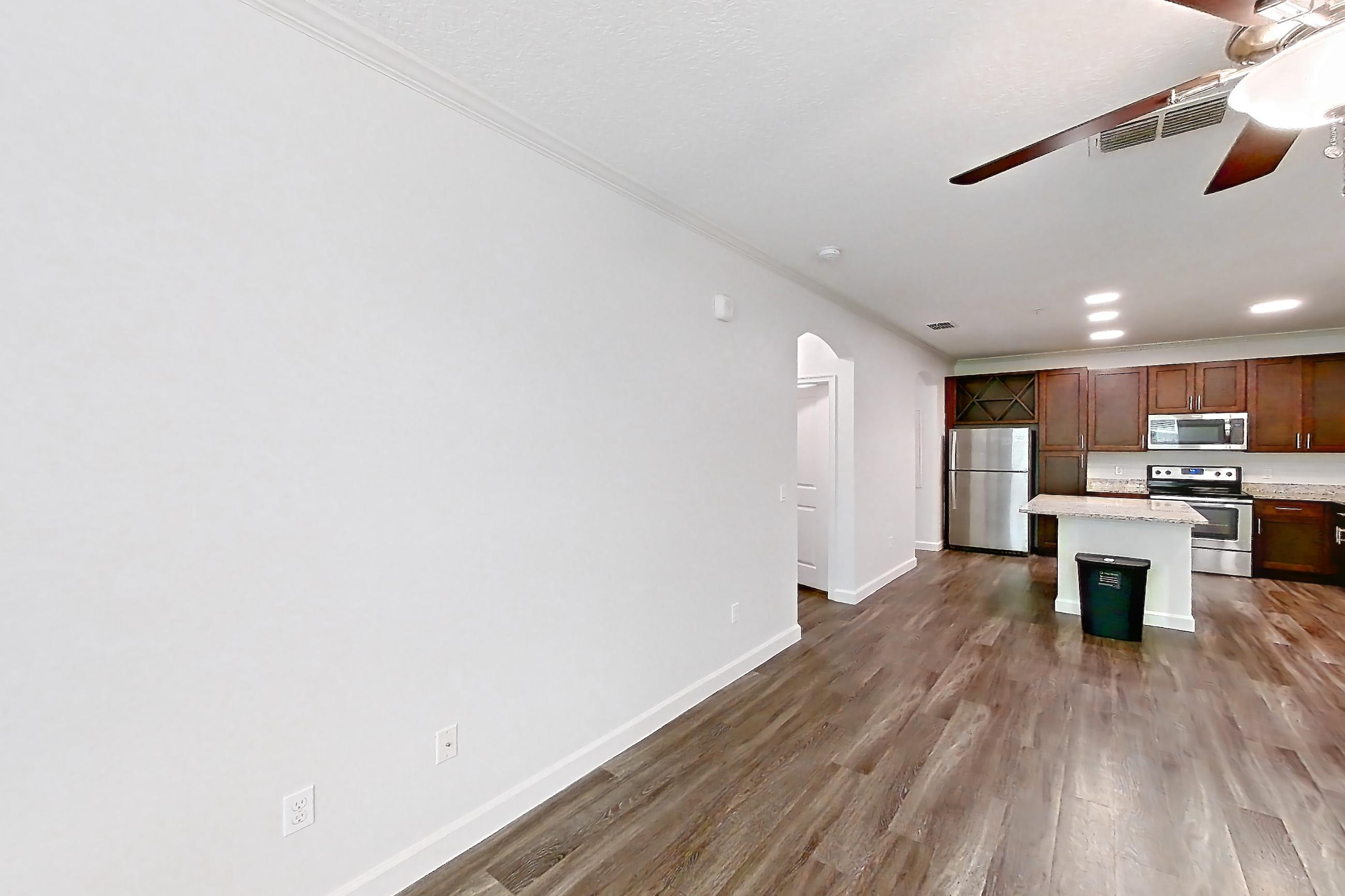 Living room with dark wood-finish flooring, electric range, light stone countertops, oven/range, and stainless steel appliances, Apartment 5013 at Lantower Grande Pines