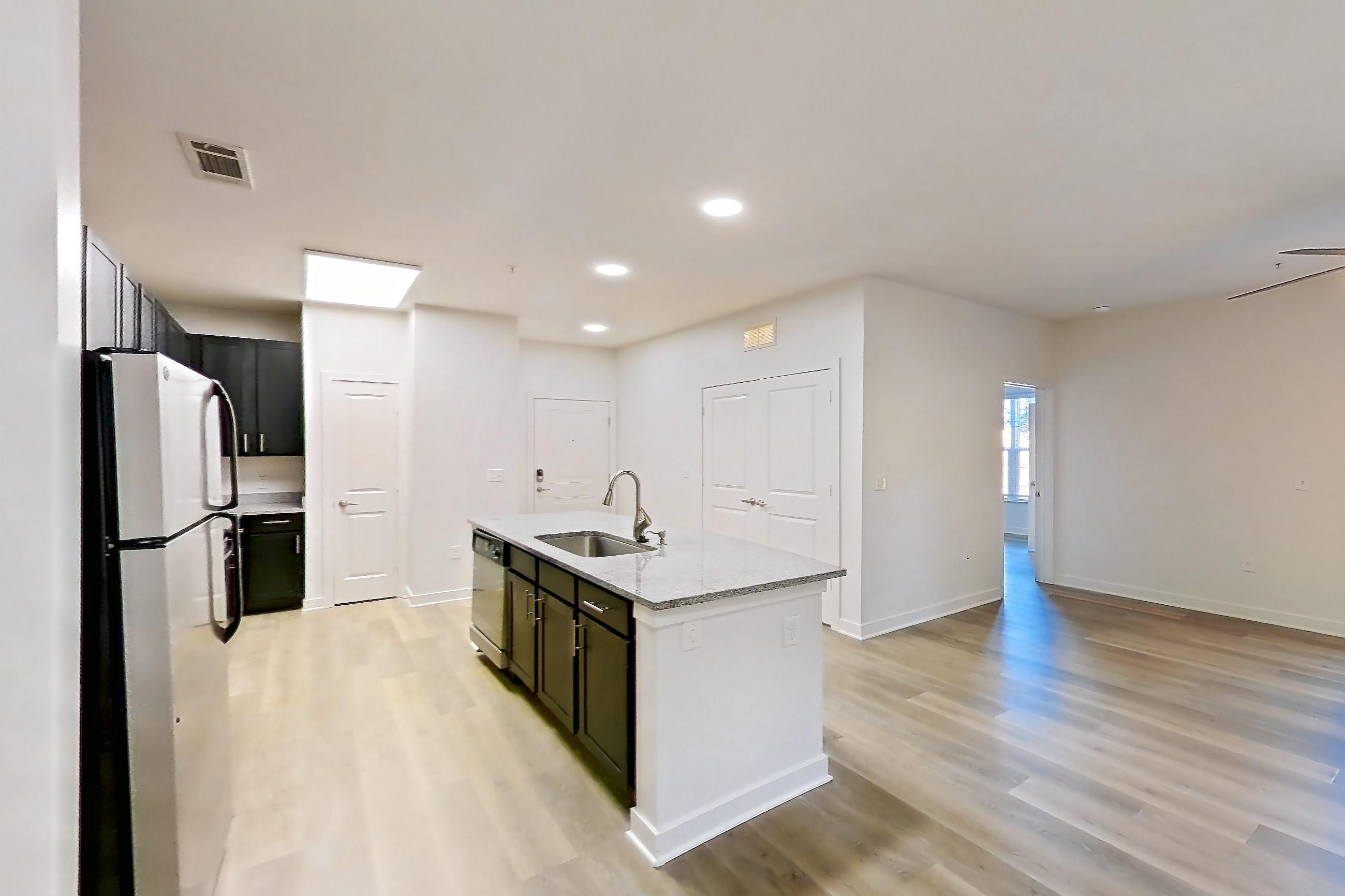 Dining room with kitchen island, light stone countertops, light wood-finish flooring, refrigerator, and white appliances, Apartment 008 at Realm at Patterson Place
