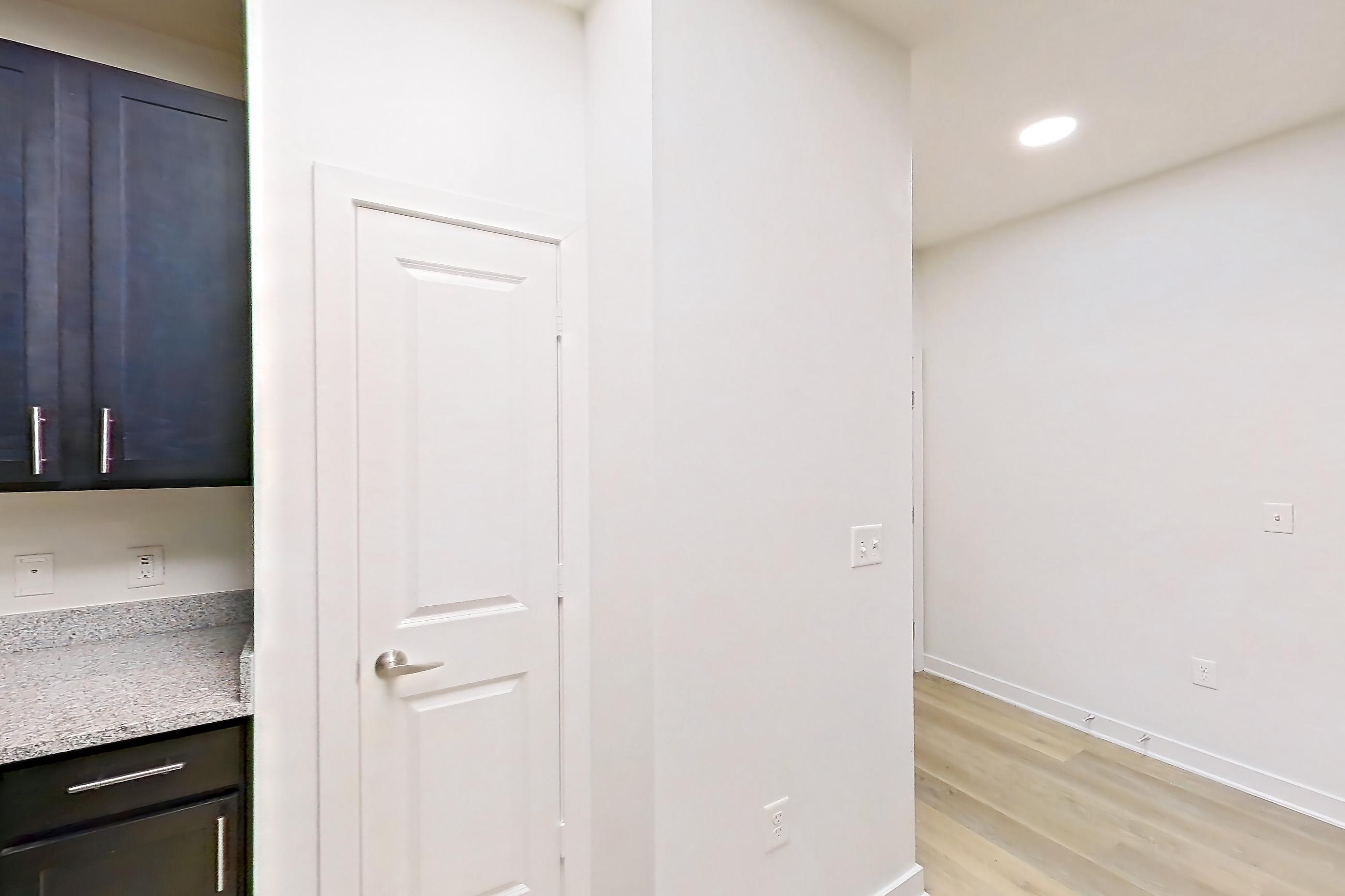 Kitchen with dishwasher, electric range, light countertops, light stone countertops, light wood-finish flooring, microwave, oven/range, refrigerator, and stainless steel appliances, Apartment 008 at Realm at Patterson Place