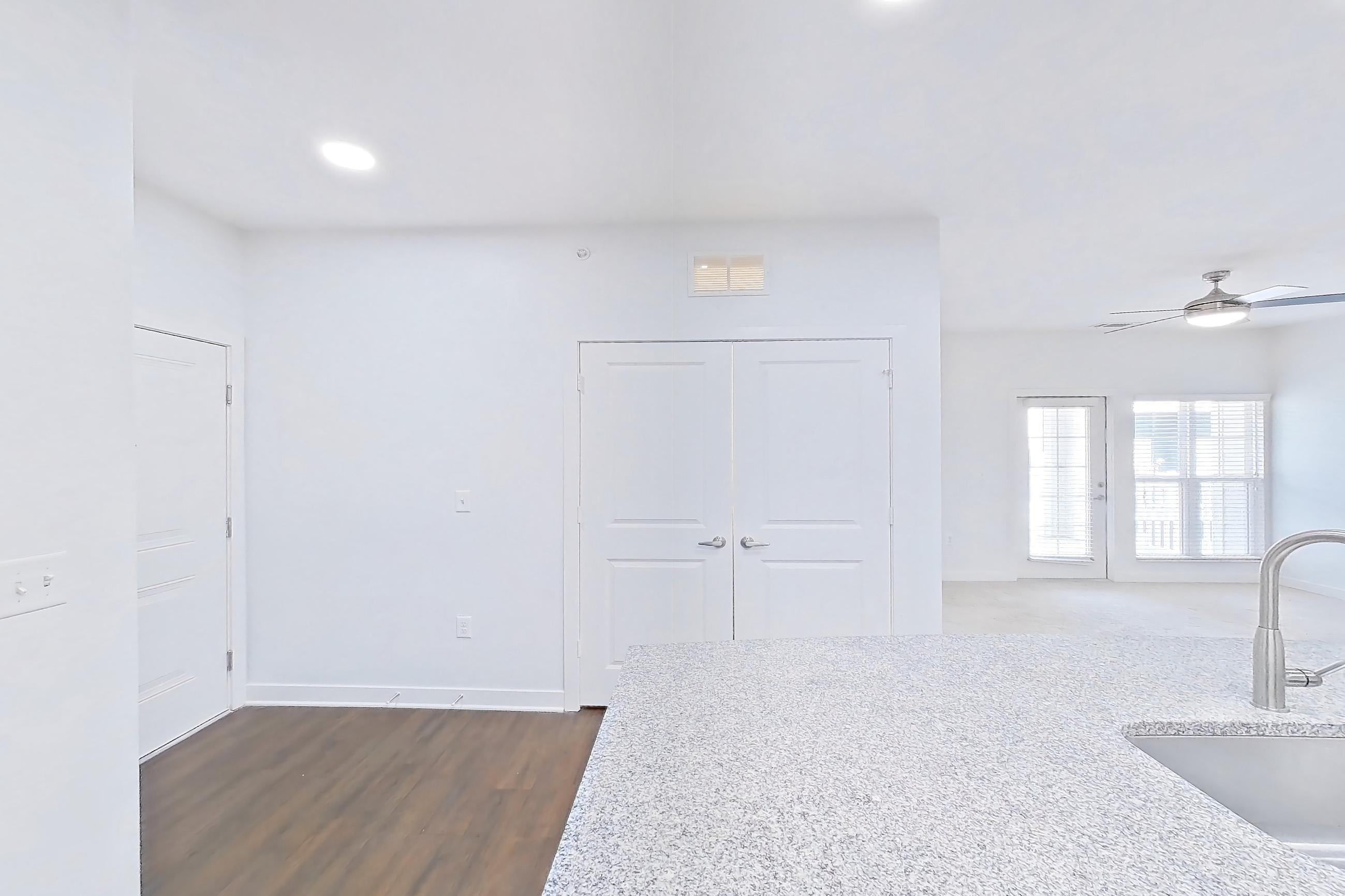 Kitchen with dark wood-finish flooring, dishwasher, electric range, light countertops, light stone countertops, light wood-finish flooring, microwave, oven/range, refrigerator, and stainless steel appliances, Apartment 208 at Realm at Patterson Place
