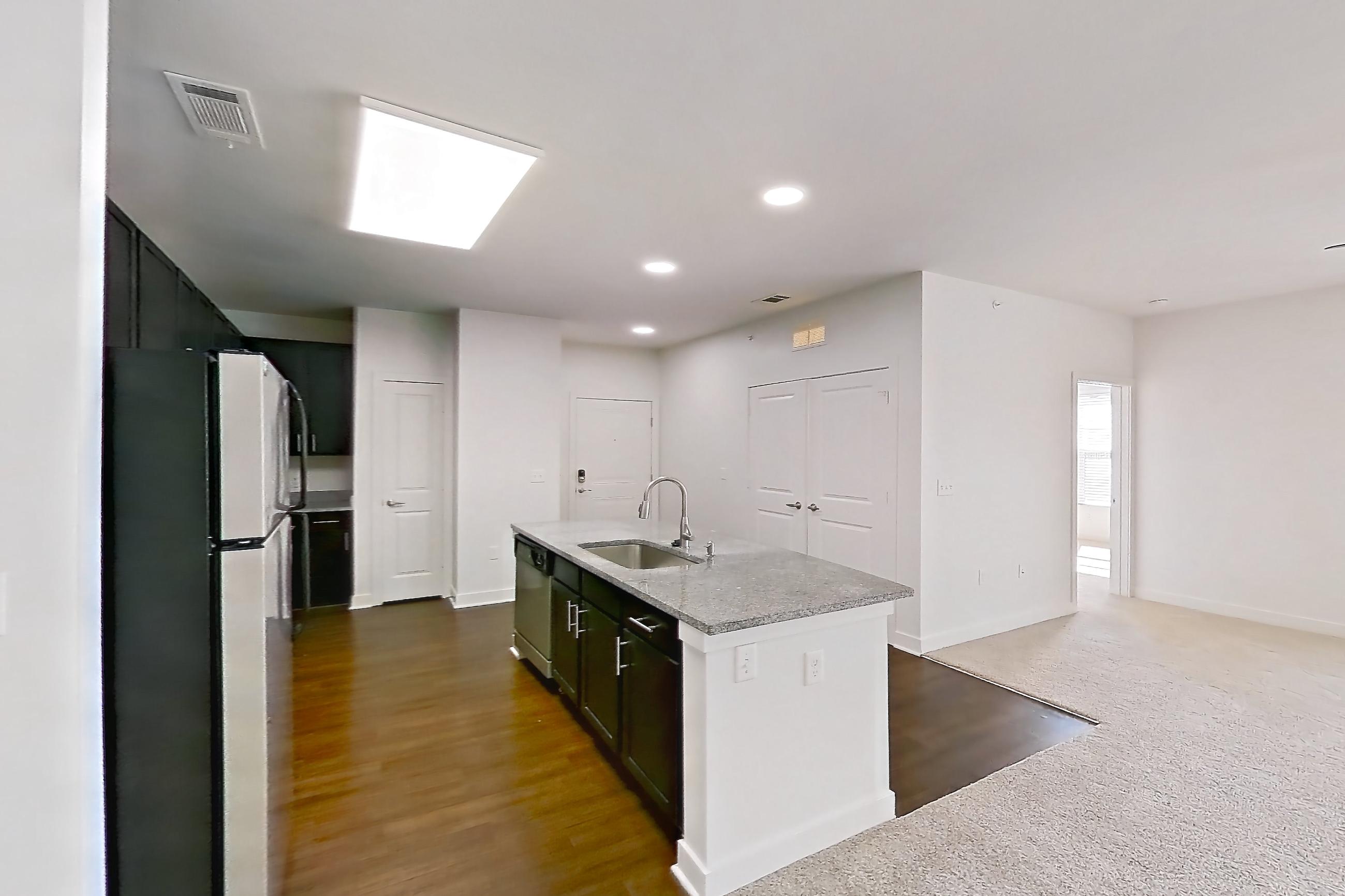 Dining room with dark carpet, dishwasher, kitchen island, light stone countertops, refrigerator, and stainless steel appliances, Apartment 301 at Realm at Patterson Place