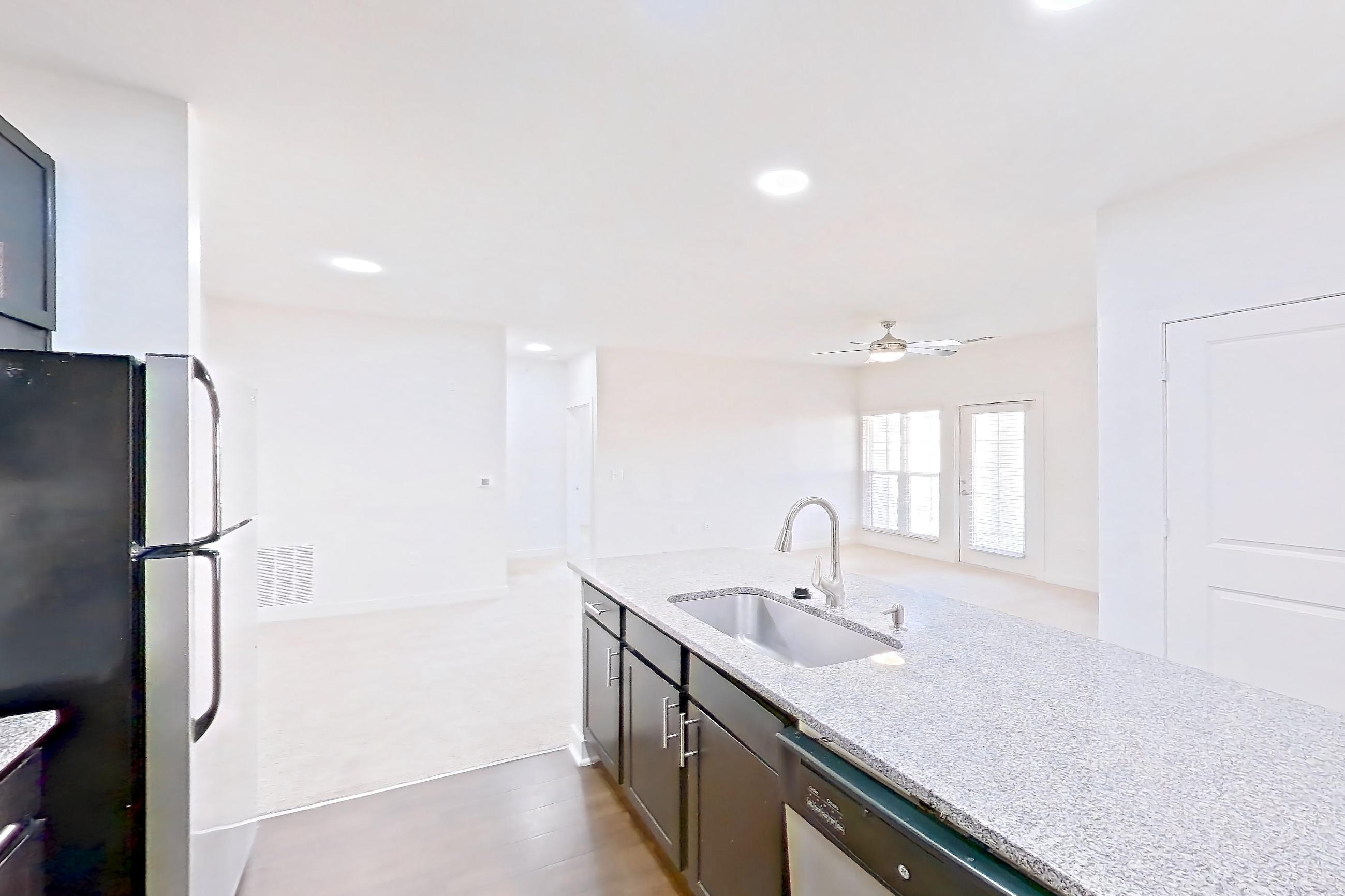 Kitchen with dark wood-finish flooring, dishwasher, electric range, light countertops, light stone countertops, microwave, oven/range, refrigerator, and stainless steel appliances, Apartment 302 at Realm at Patterson Place