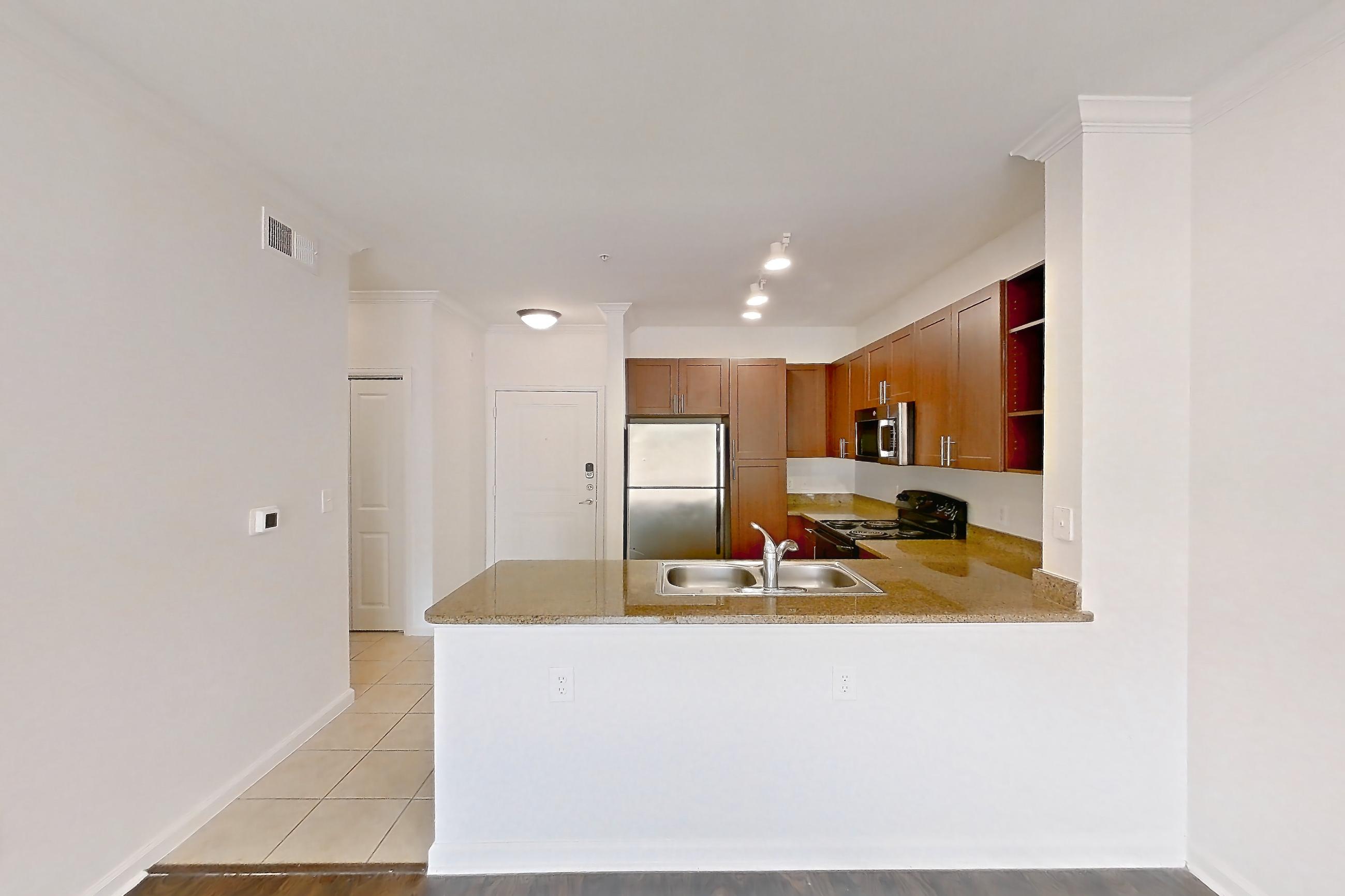 Dining room with black appliances, electric range, light countertops, light stone countertops, light wood-finish flooring, oven/range, refrigerator, and stainless steel appliances, Apartment 1023 at The Cortona