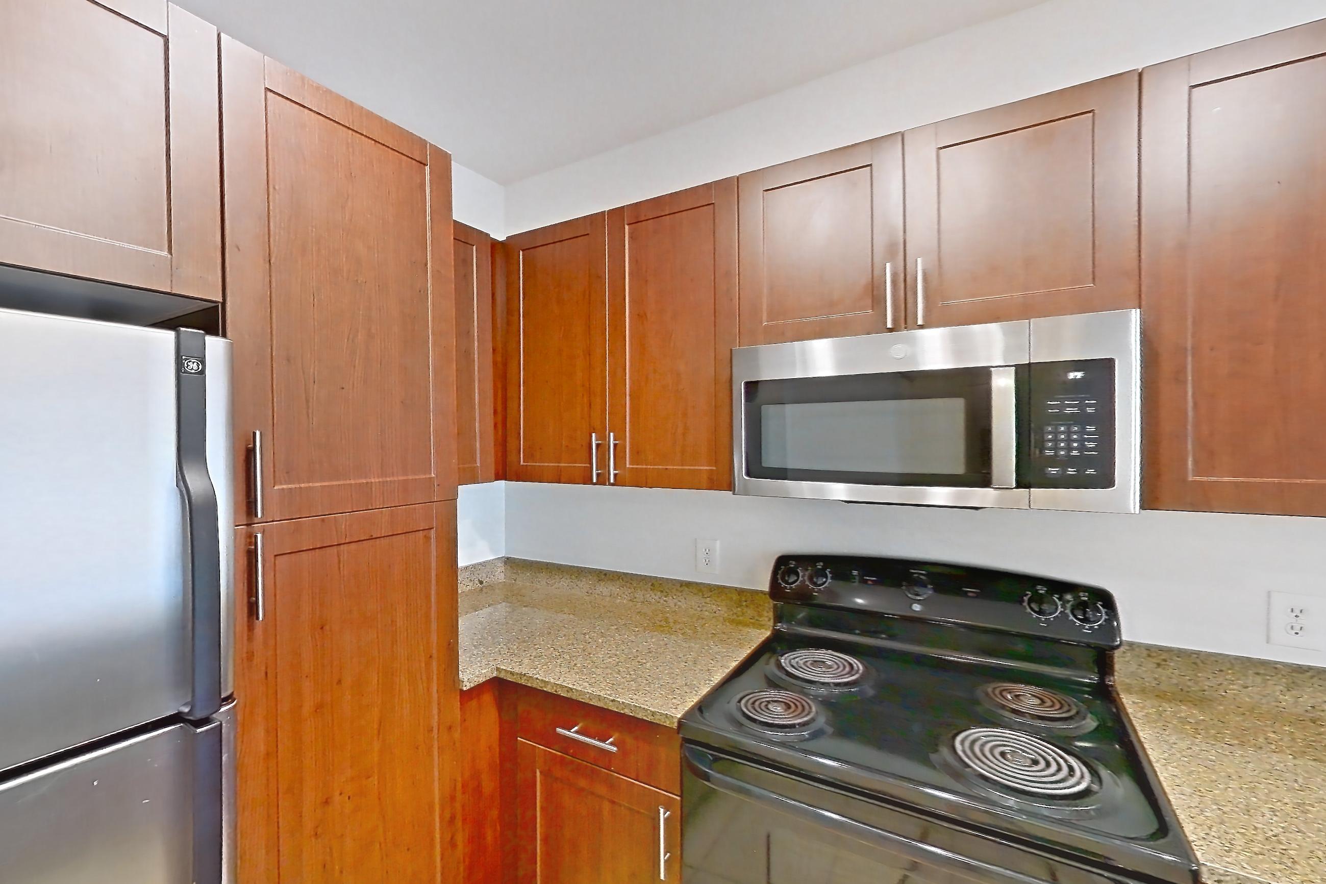 Kitchen with black appliances, dishwasher, electric range, light stone countertops, light tile flooring, microwave, oven/range, and stainless steel appliances, Apartment 1023 at The Cortona