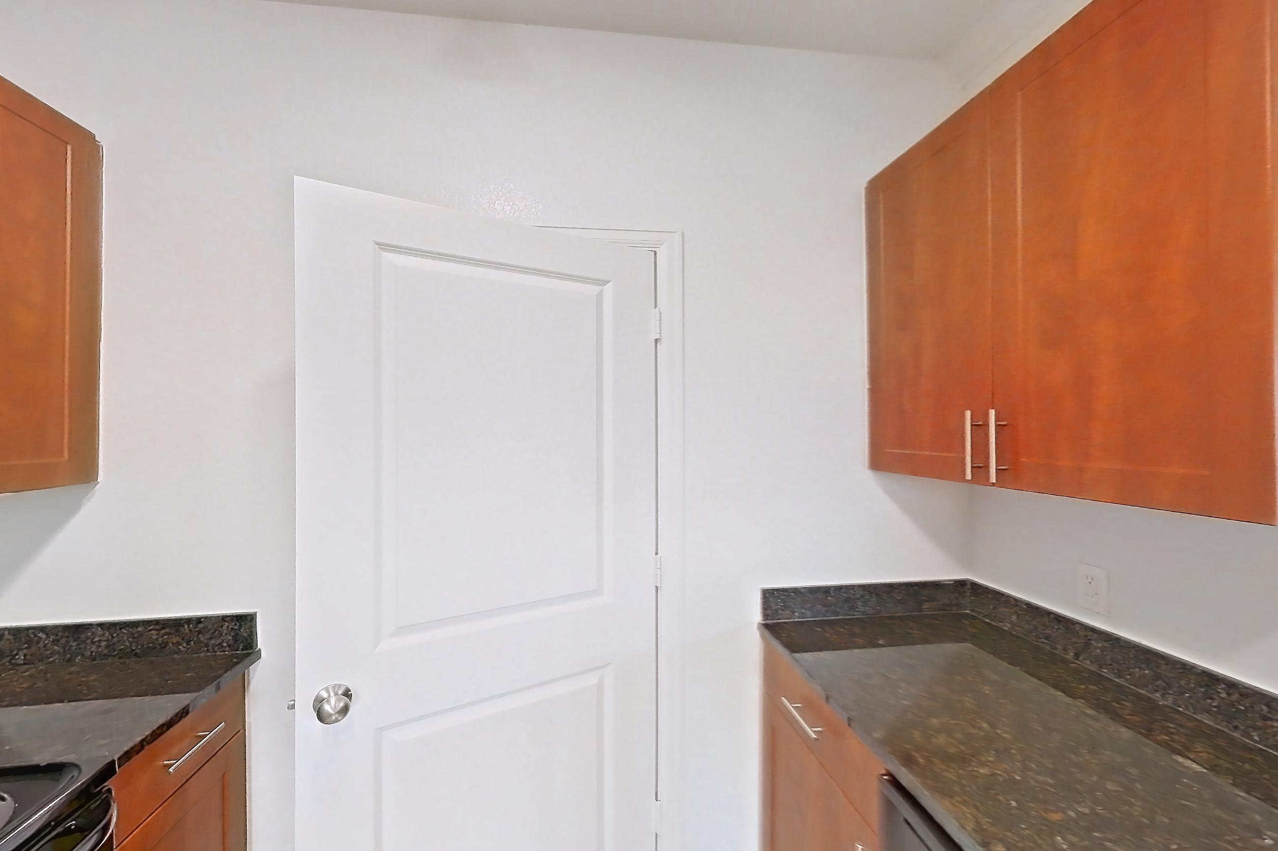 Kitchen with black appliances, dark stone countertops, dishwasher, light carpet, light tile flooring, and refrigerator, Apartment 1031 at The Cortona