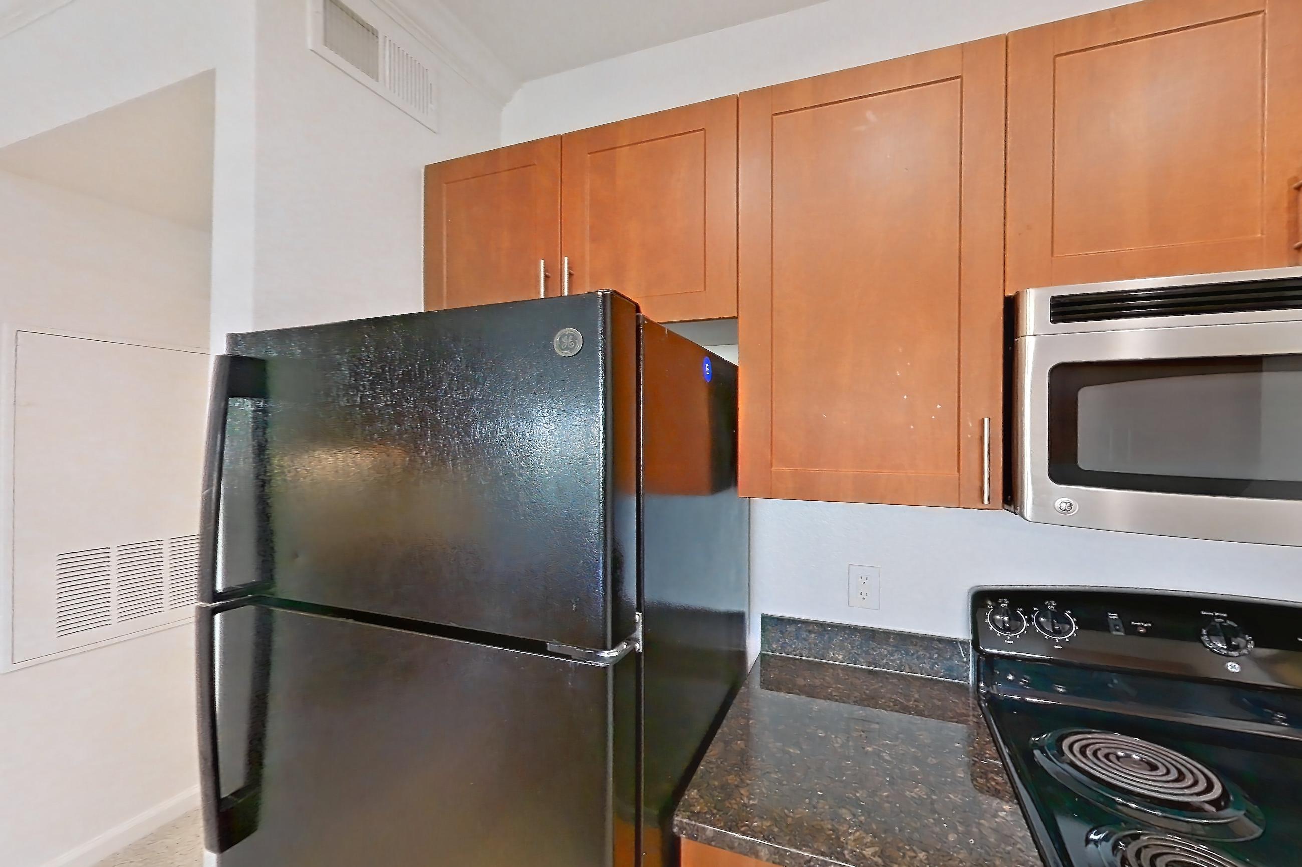 Kitchen with black appliances, dark stone countertops, dishwasher, light carpet, light tile flooring, and refrigerator, Apartment 1031 at The Cortona