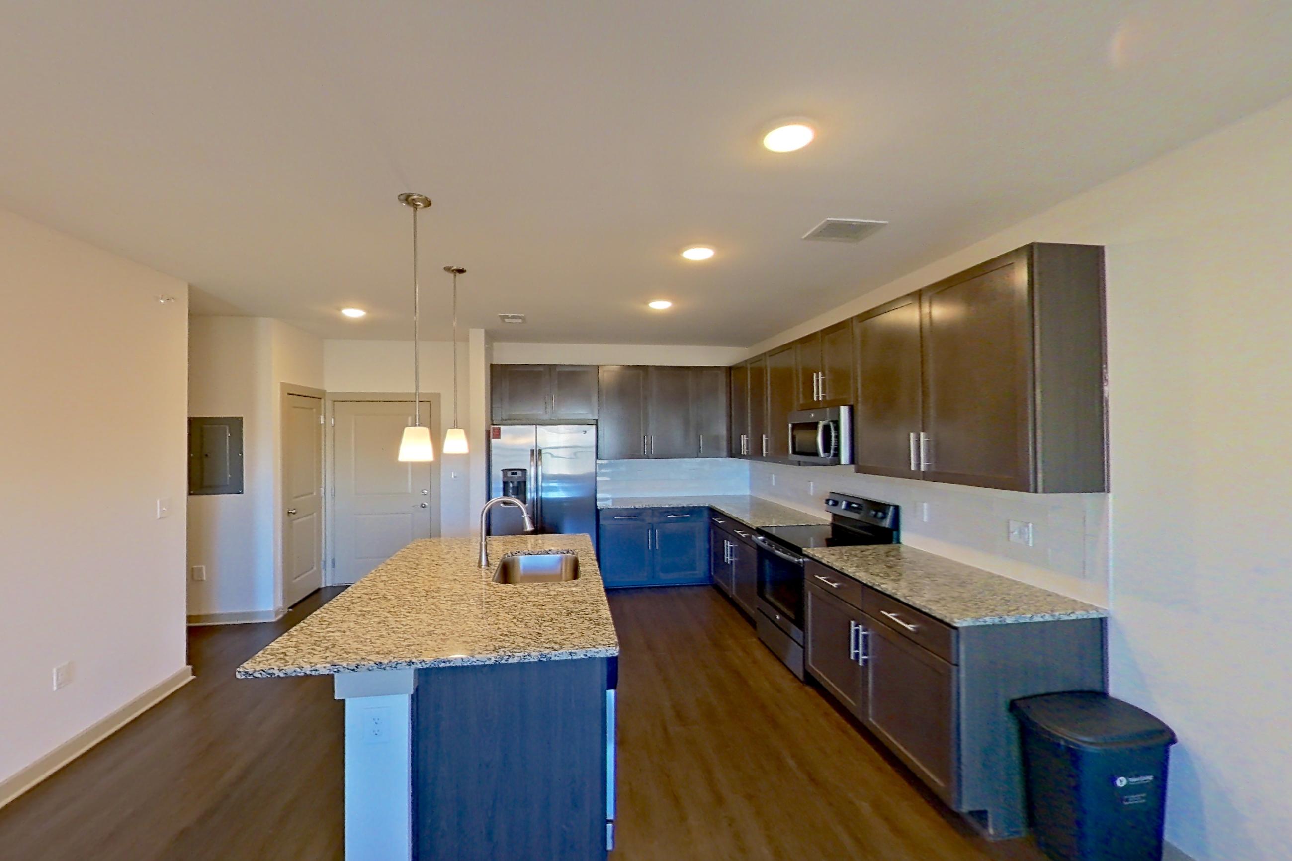 Living space with dark wood-finish flooring, electric range, light stone countertops, oven/range, and stainless steel appliances, Apartment 1-506 at Aventine Northshore
