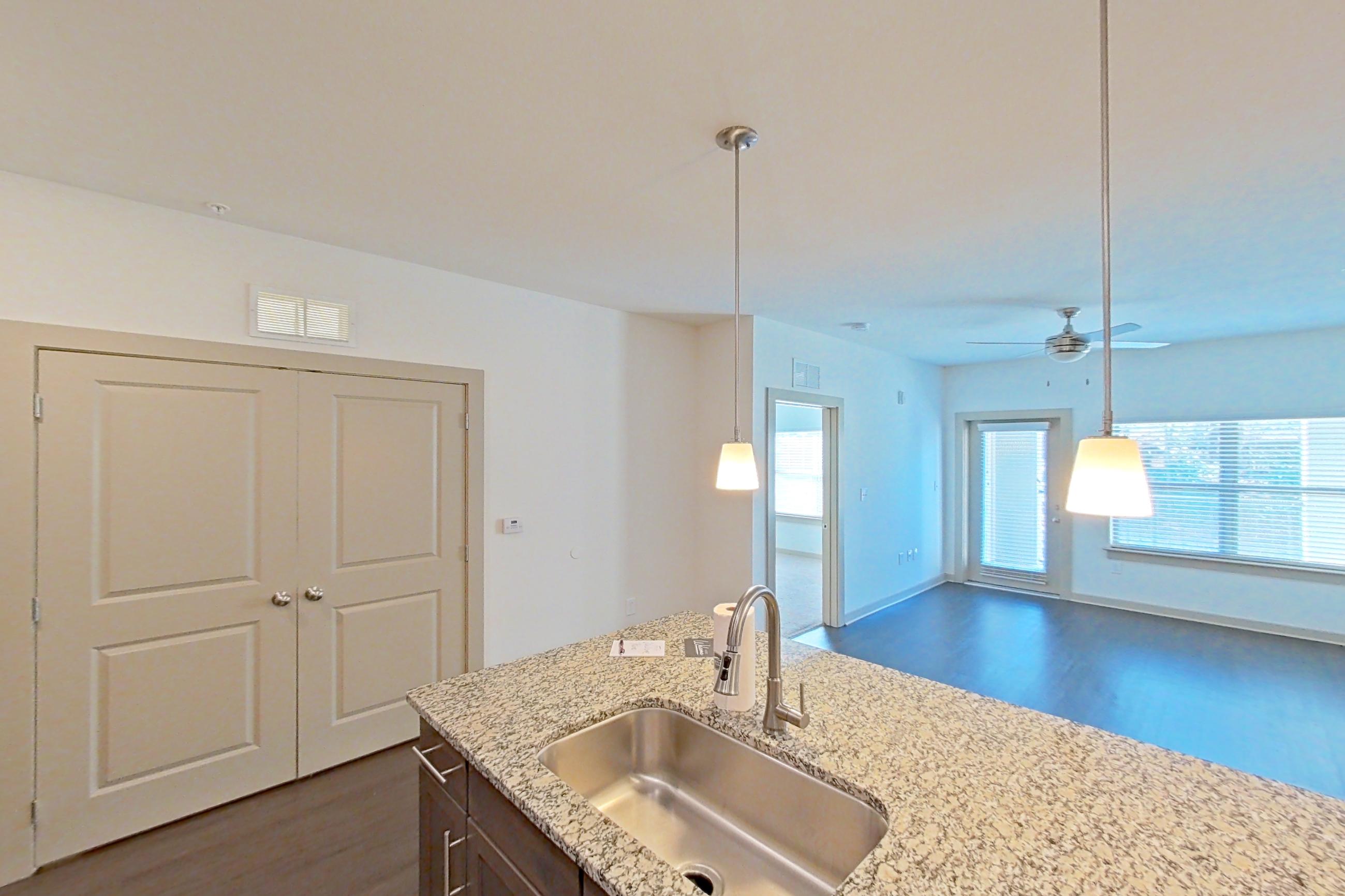 Kitchen with dark wood-finish flooring, dishwasher, electric range, light countertops, light stone countertops, microwave, oven/range, refrigerator, stainless steel appliances, and water & ice dispenser, Apartment 6-300 at Aventine Northshore