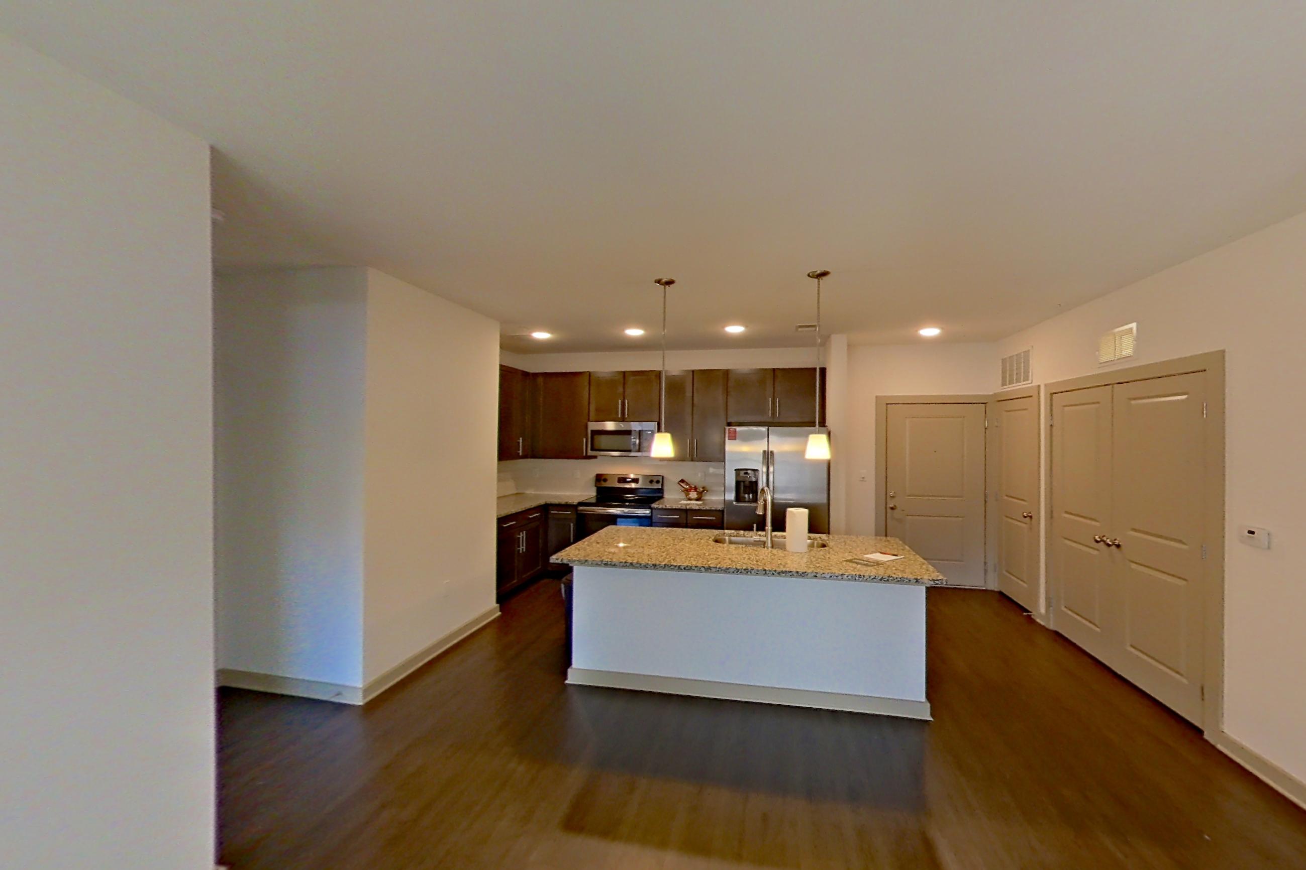 Living space with dark wood-finish flooring, electric range, light stone countertops, oven/range, refrigerator, stainless steel appliances, and water & ice dispenser, Apartment 6-300 at Aventine Northshore