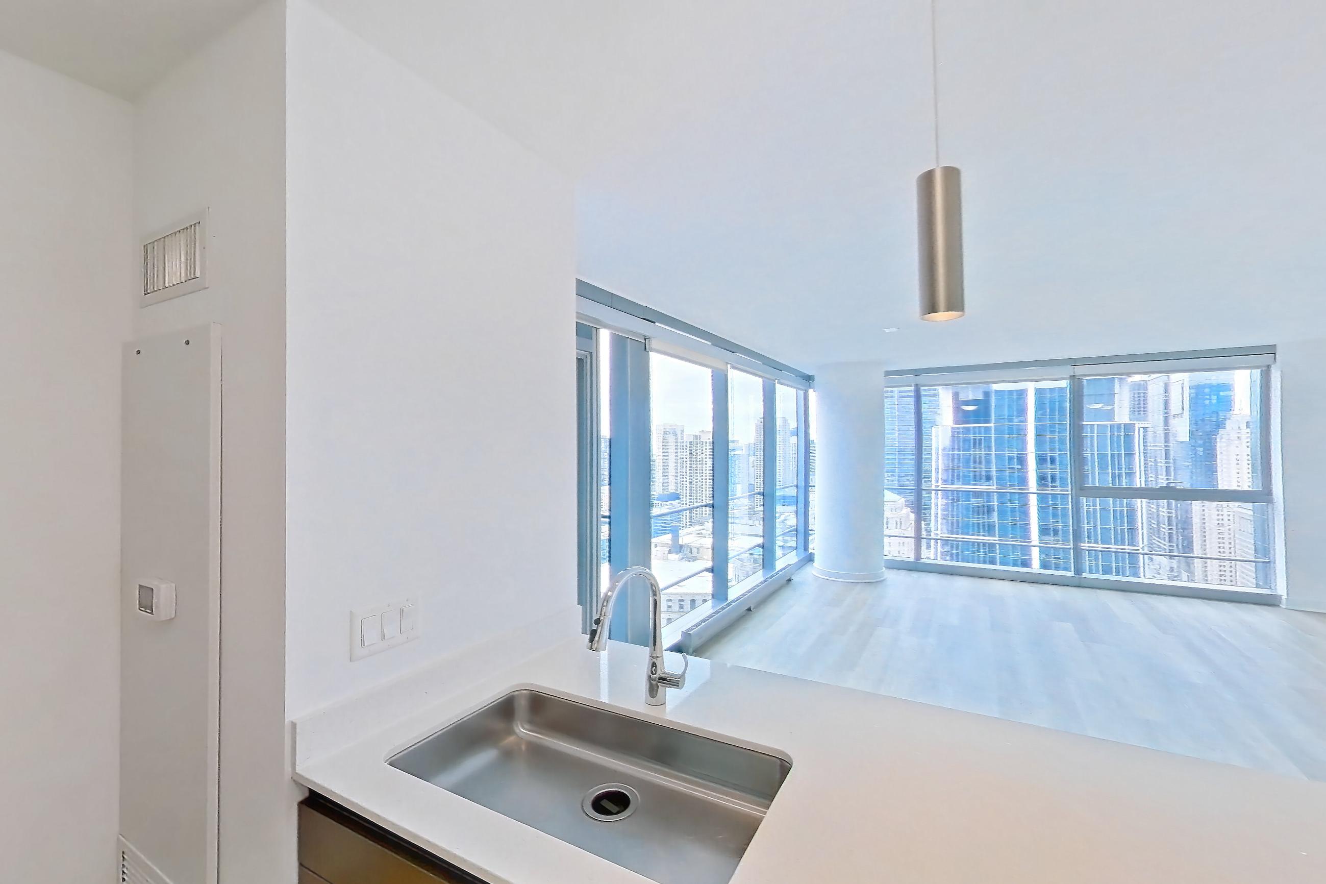 Kitchen with gas range, kitchen island, light countertops, light stone countertops, light wood-finish flooring, oven/range, range hood, and stainless steel appliances, Apartment 4307 at Wolf Point West