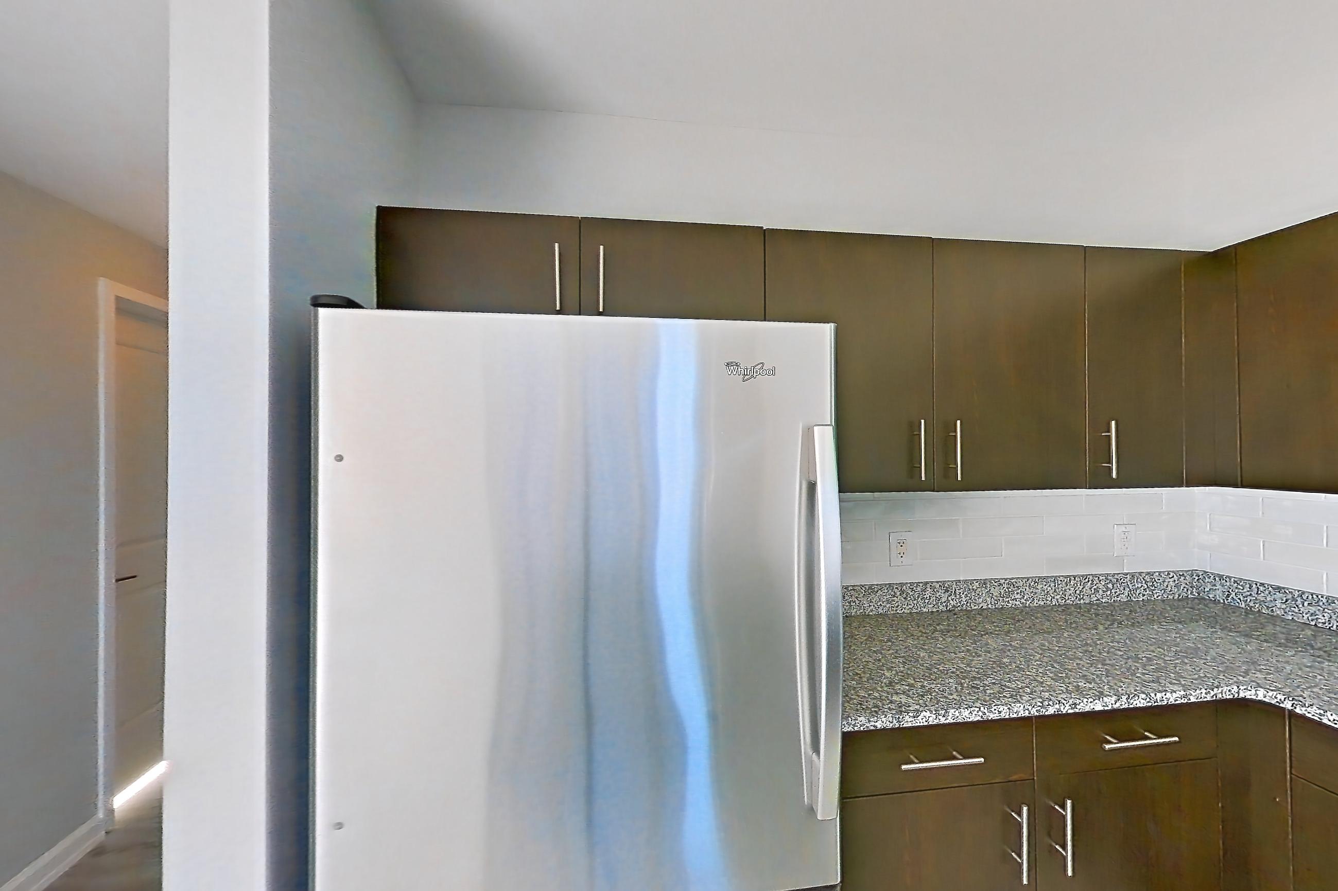 Kitchen with dark stone countertops, dishwasher, electric range, light stone countertops, light tile flooring, microwave, oven/range, refrigerator, and stainless steel appliances, Apartment RT-0922 at RiverTrace at Port Imperial