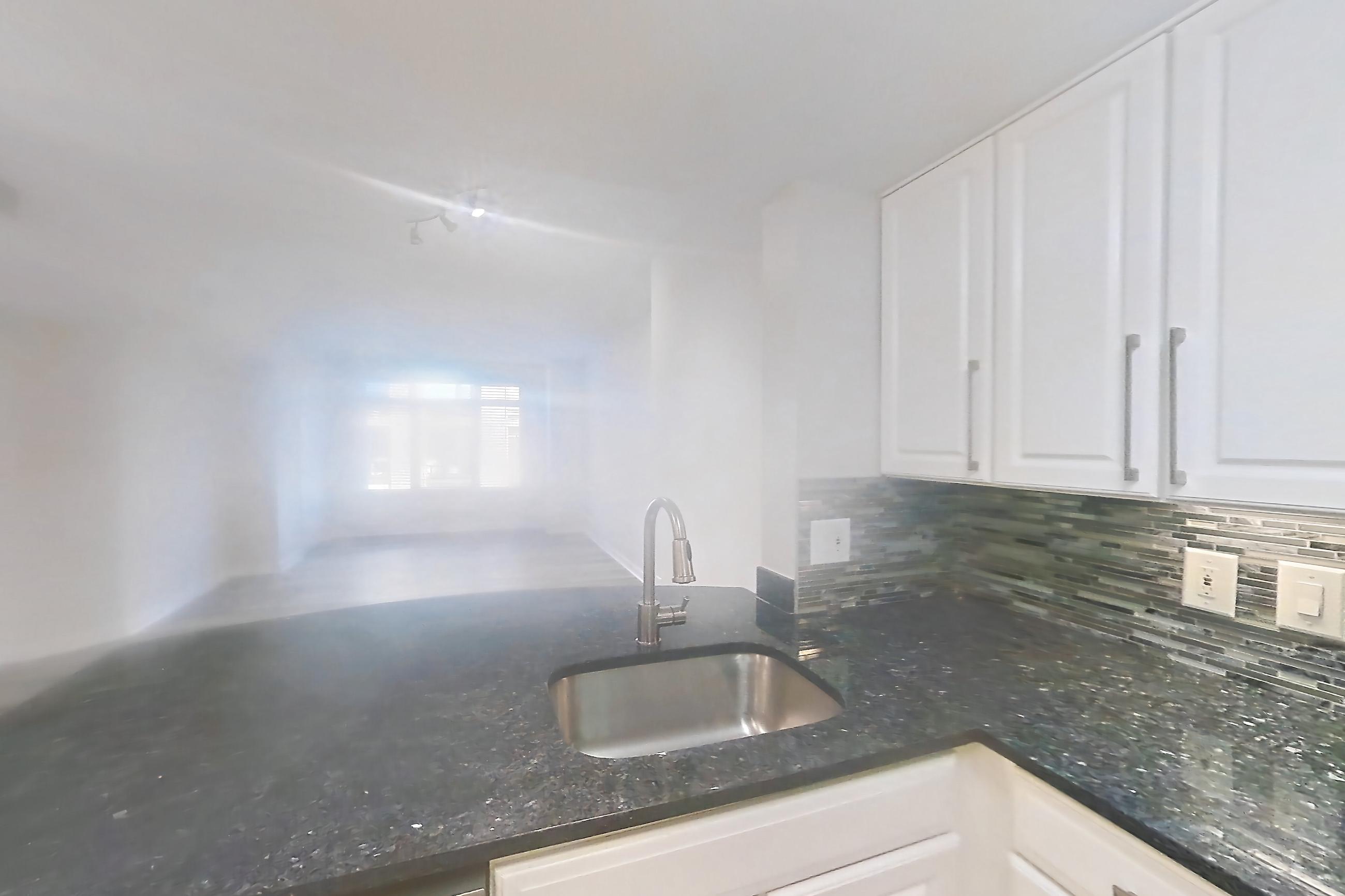 Kitchen with dark stone countertops, dishwasher, gas range, light countertops, light wood-finish flooring, oven/range, refrigerator, and stainless steel appliances, Apartment 1023 at The Barton at Woodley