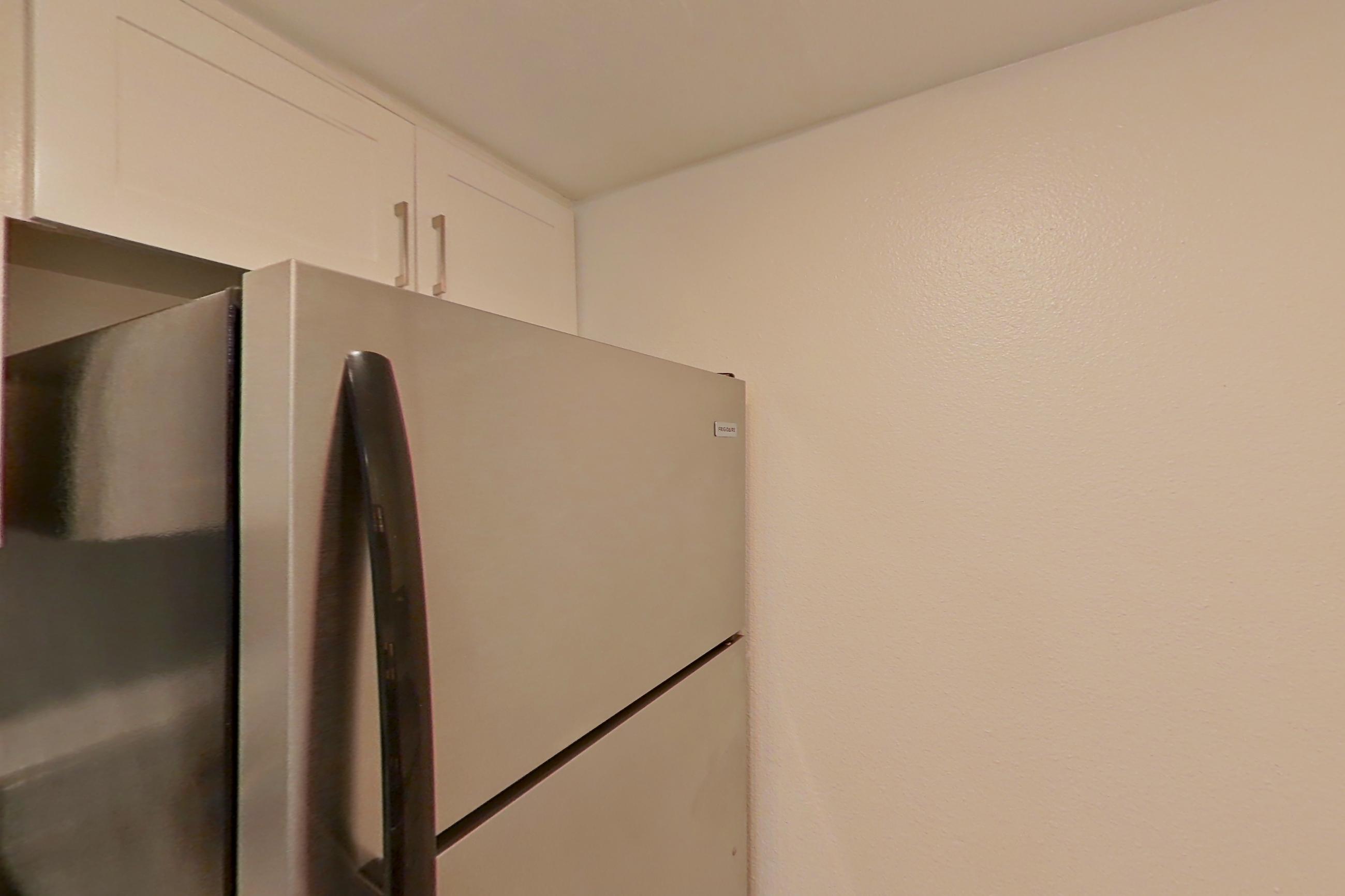 Kitchen with electric range, light countertops, light stone countertops, light wood-finish flooring, oven/range, range hood, refrigerator, and stainless steel appliances, Apartment 06 at Avana Rancho Cucamonga