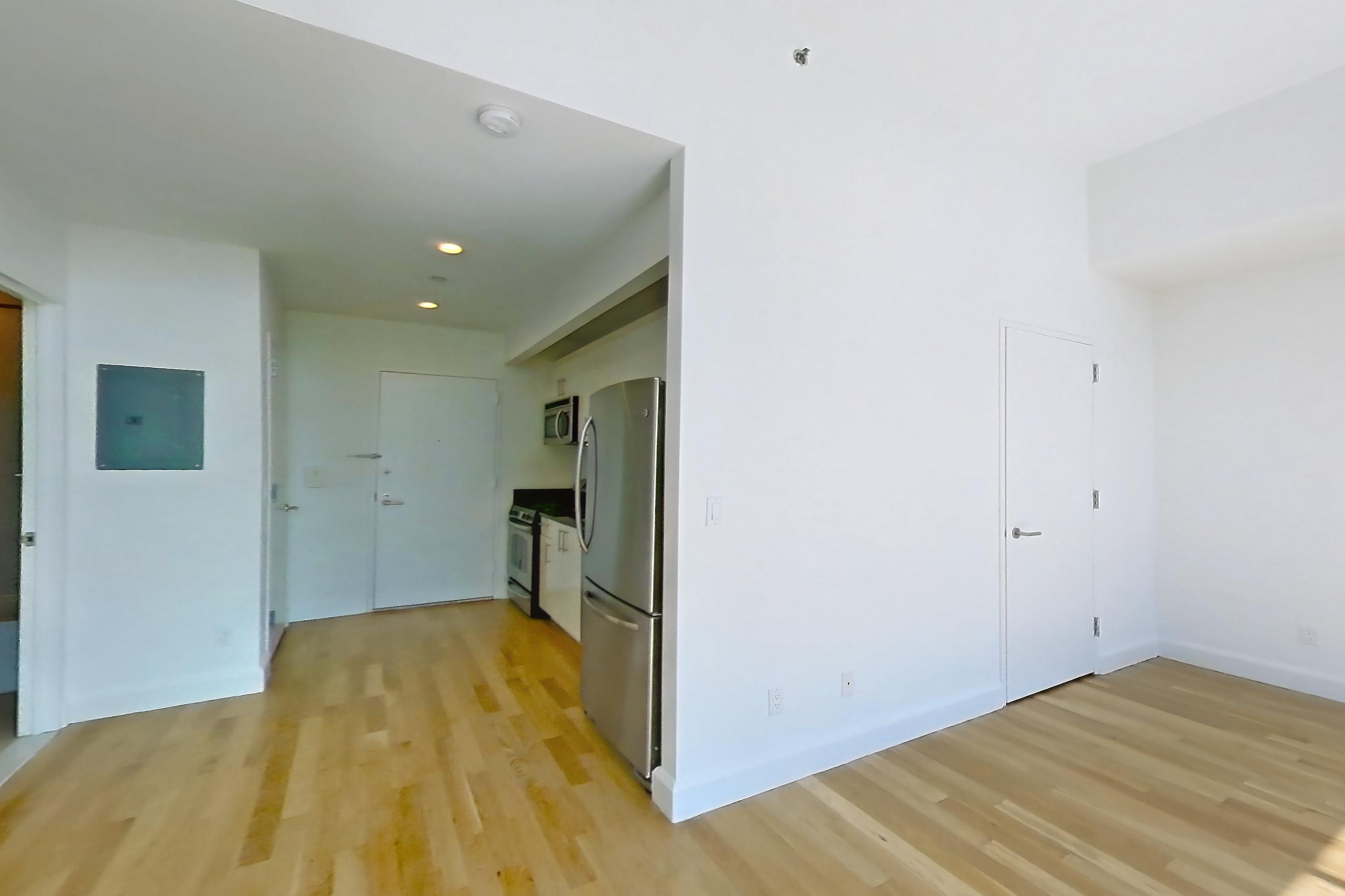 Living space with light wood-finish flooring, oven/range, refrigerator, stainless steel appliances, and white appliances, Apartment 27D at The Addison