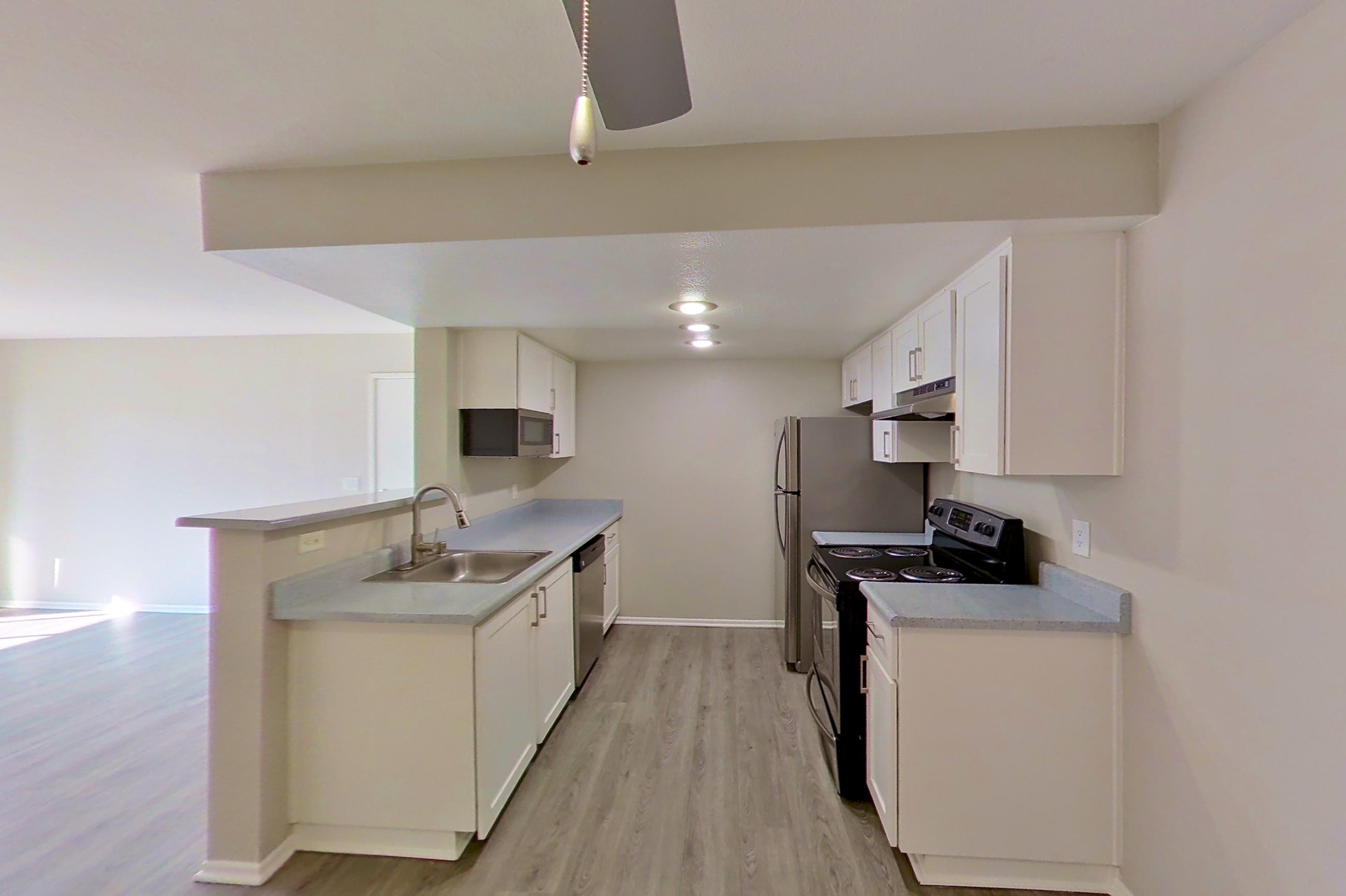 Dining area with dark wood-finish flooring, dishwasher, light countertops, light wood-finish flooring, and stainless steel appliances, Apartment 02 at Avana Rancho Cucamonga