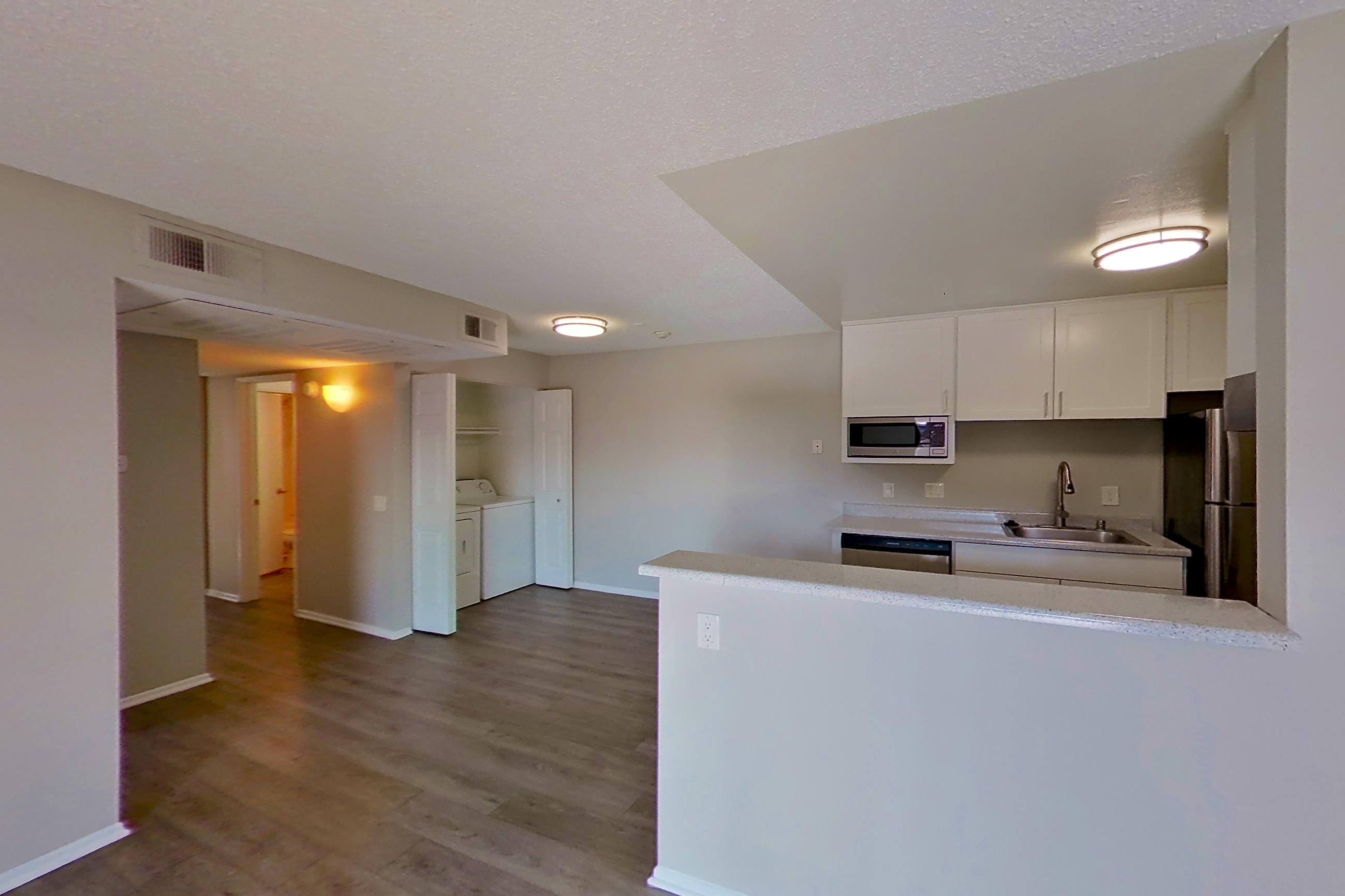 Living room with dark wood-finish flooring and in-unit laundry, Apartment 16-09 at Avana Rancho Cucamonga