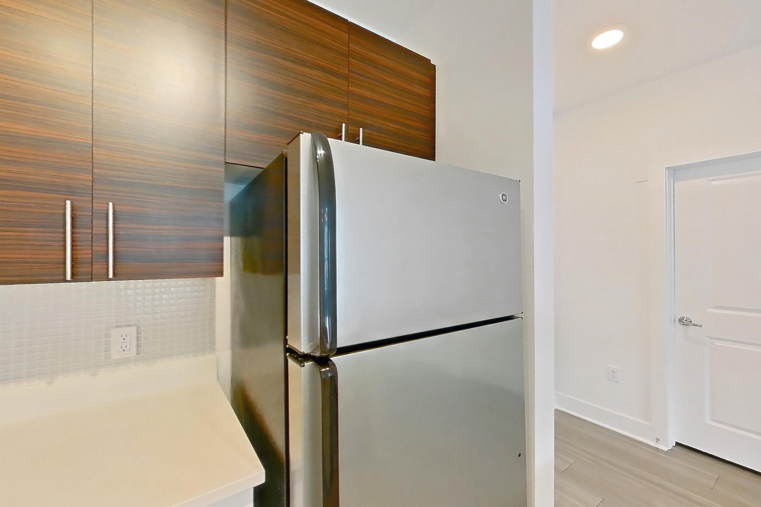 Kitchen with dishwasher, electric range, light countertops, light wood-finish flooring, oven/range, refrigerator, and stainless steel appliances, Apartment 4108 at NoHo Flats