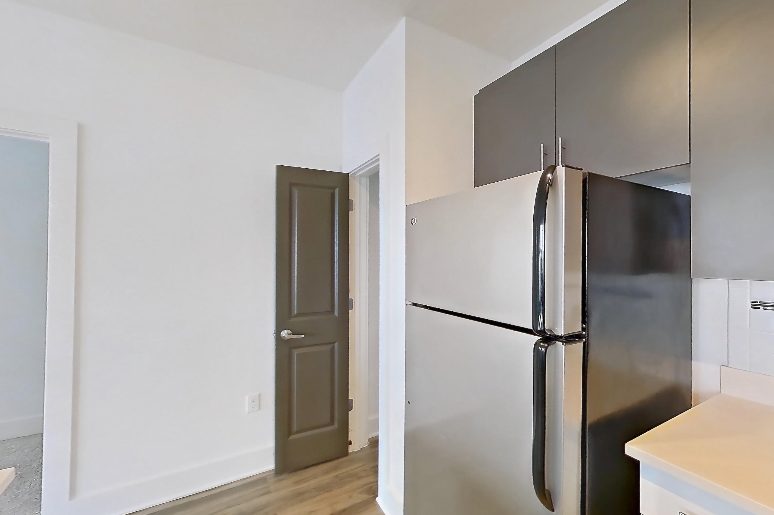 Kitchen with dark wood-finish flooring, dishwasher, light countertops, light wood-finish flooring, oven/range, refrigerator, stainless steel appliances, and white appliances, Apartment 1311 at NoHo Flats