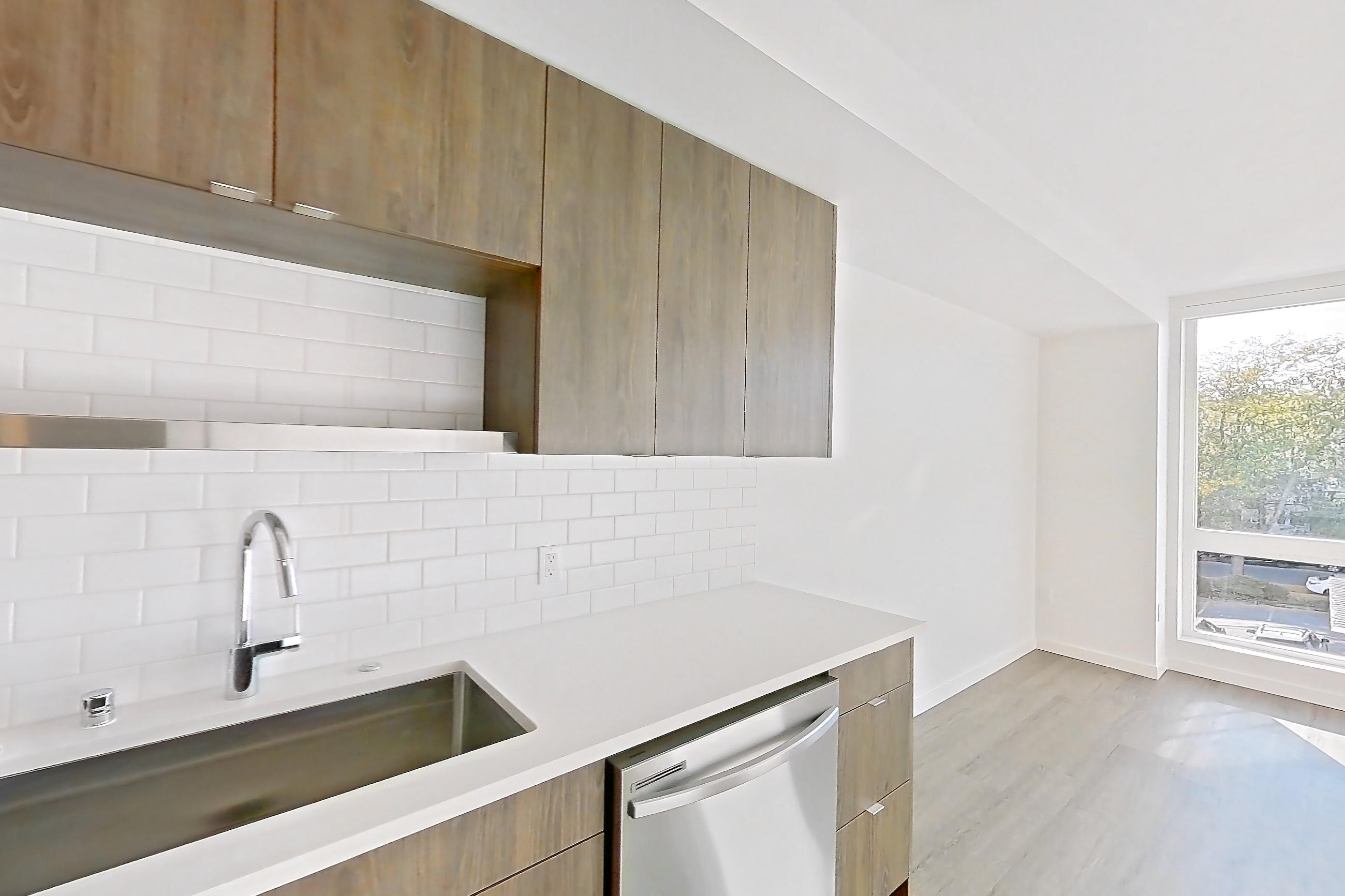 Kitchen with dishwasher, electric range, light countertops, light stone countertops, light wood-finish flooring, microwave, mini-split AC, oven/range, and stainless steel appliances, Apartment 416 at The Cline