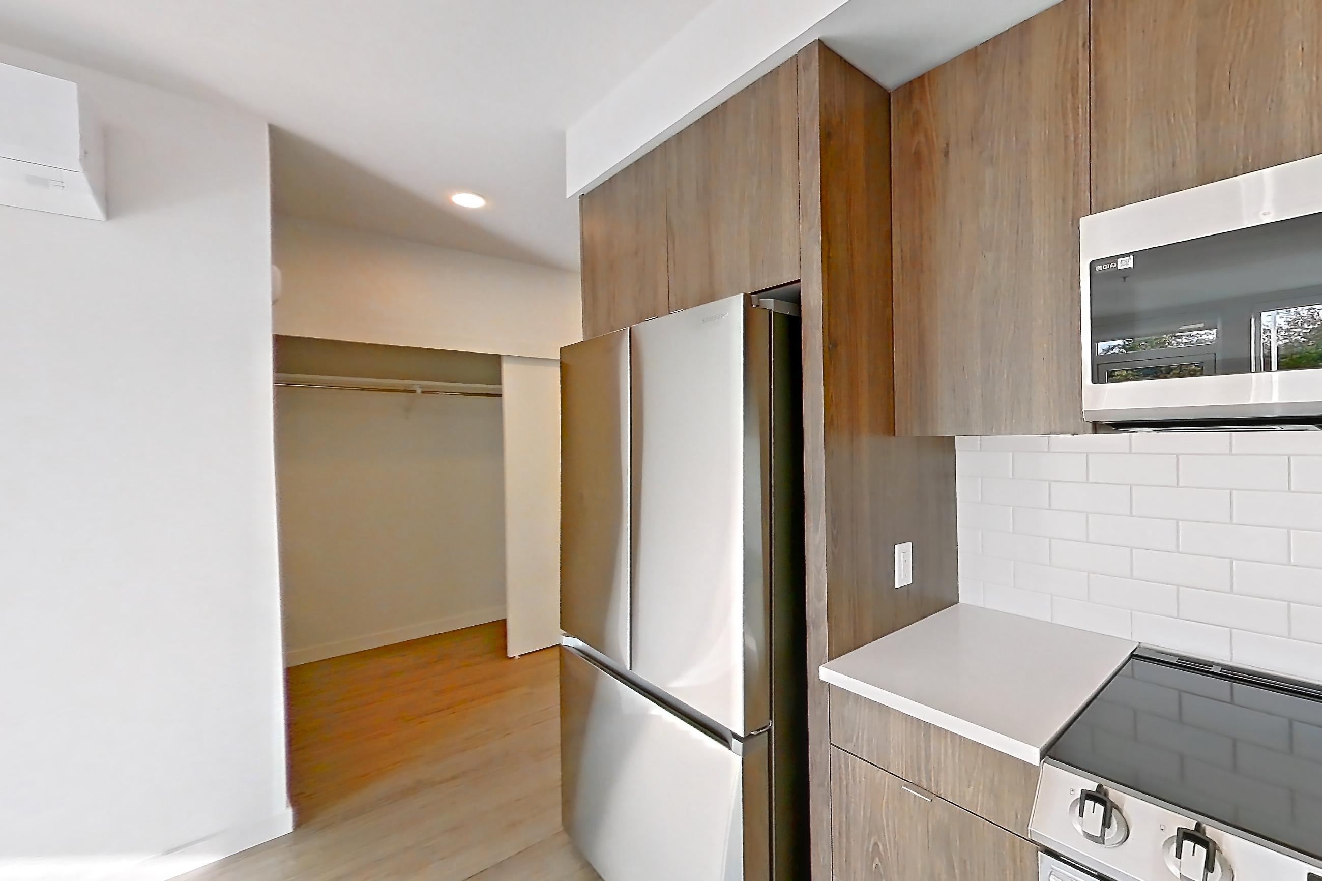Kitchen with dishwasher, electric range, light countertops, light stone countertops, light wood-finish flooring, microwave, mini-split AC, oven/range, and stainless steel appliances, Apartment 416 at The Cline