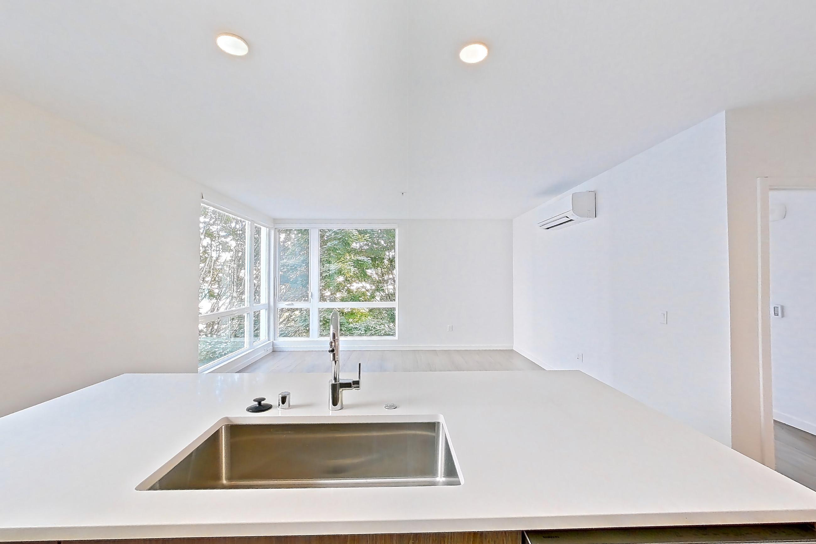 Kitchen with cooktop, dishwasher, electric cooktop, electric range, light countertops, light stone countertops, light wood-finish flooring, microwave, oven/range, refrigerator, and stainless steel appliances, Apartment 403 at The Cline