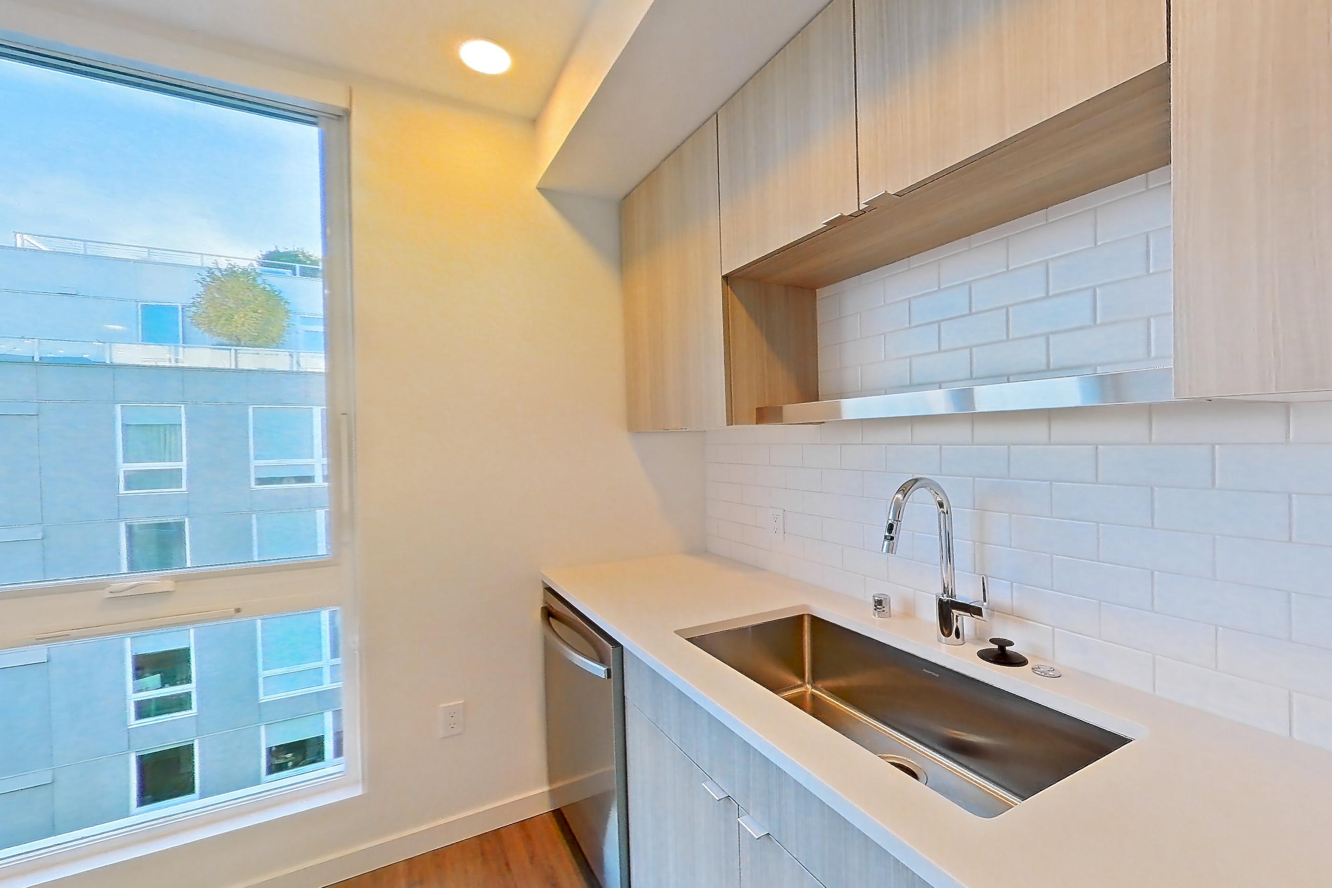 Kitchen with dishwasher, electric range, light countertops, light stone countertops, light wood-finish flooring, microwave, mini-split AC, oven/range, refrigerator, and stainless steel appliances, Apartment 733 at The Cline