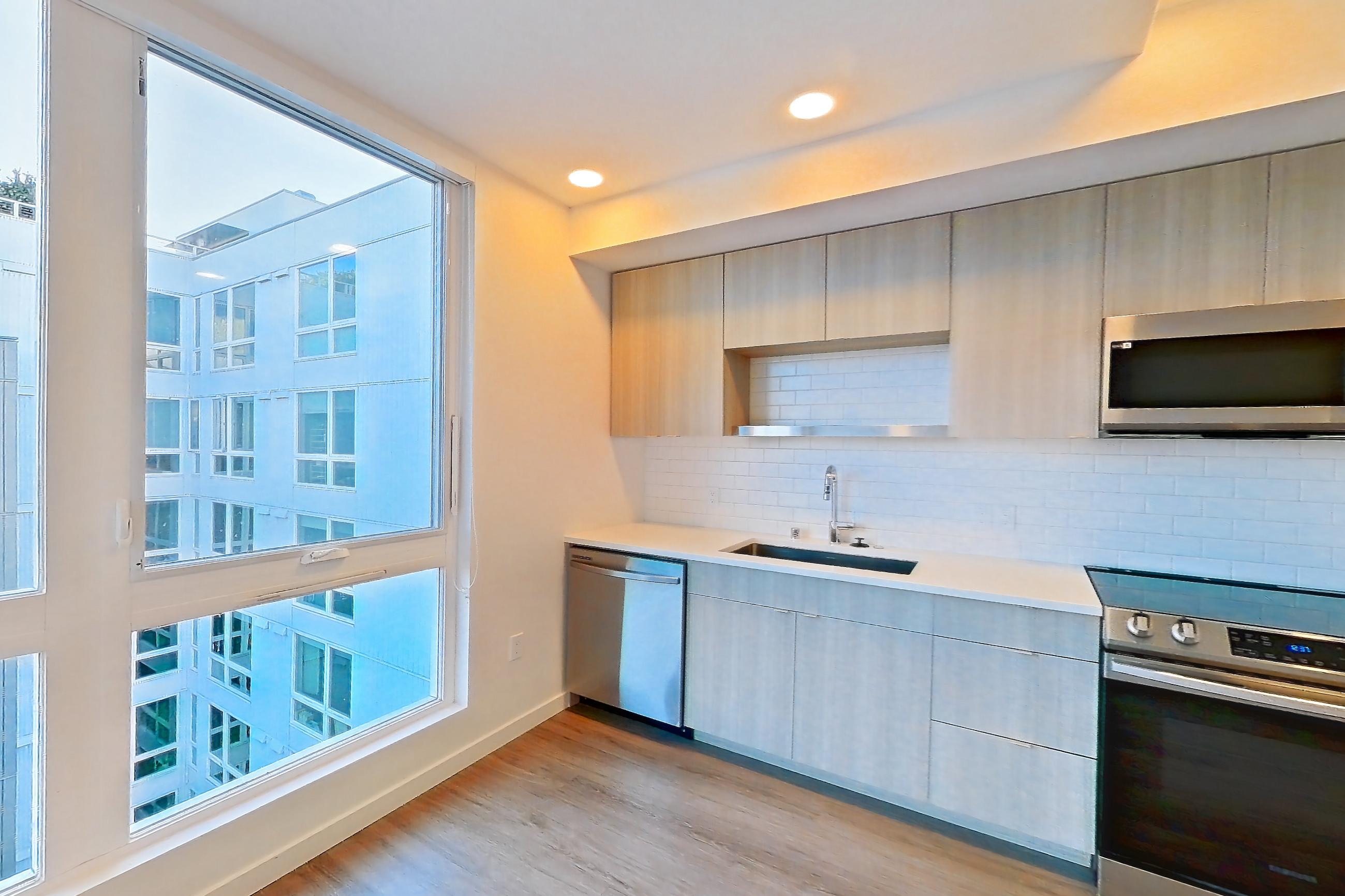 Living room with dishwasher, electric range, light stone countertops, light wood-finish flooring, microwave, oven/range, refrigerator, and stainless steel appliances, Apartment 733 at The Cline