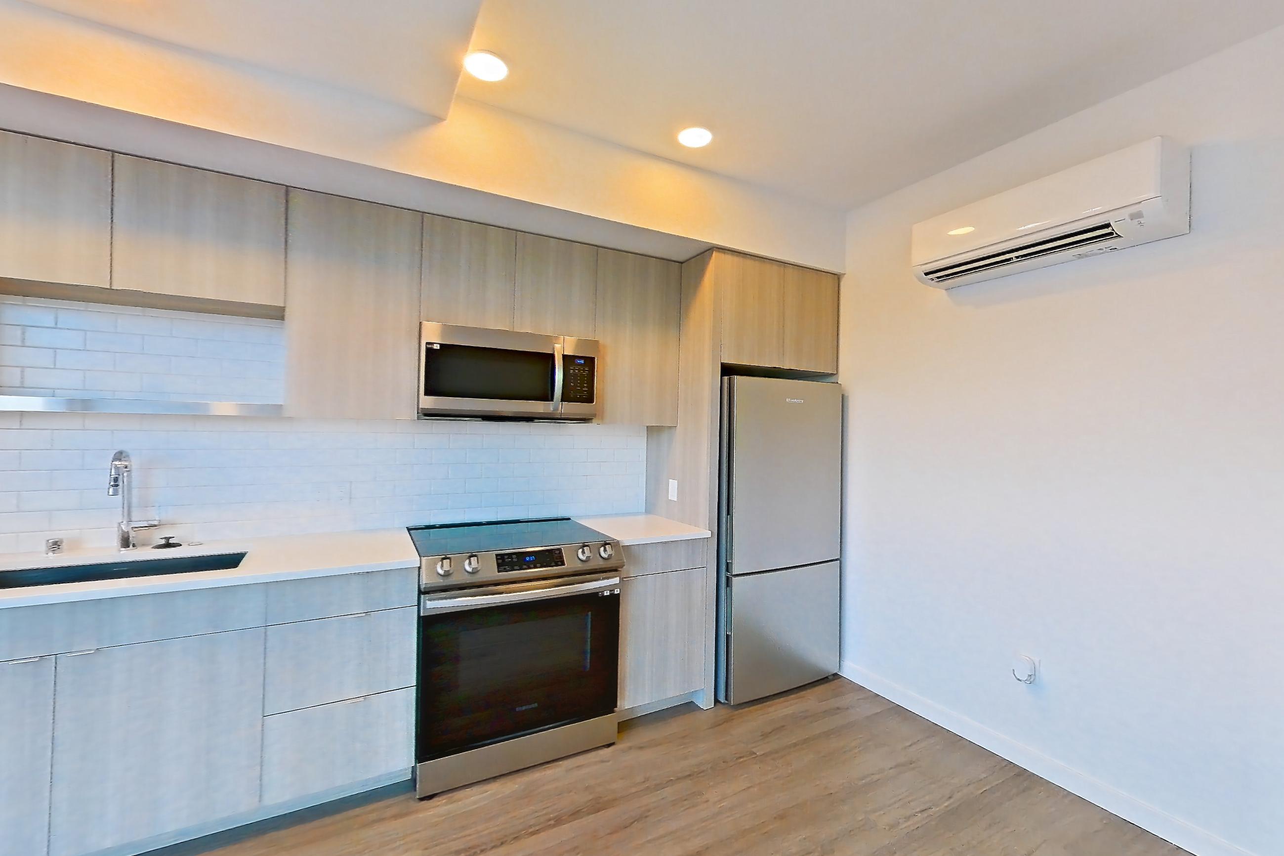 Living room with dishwasher, electric range, light stone countertops, light wood-finish flooring, microwave, oven/range, refrigerator, and stainless steel appliances, Apartment 733 at The Cline