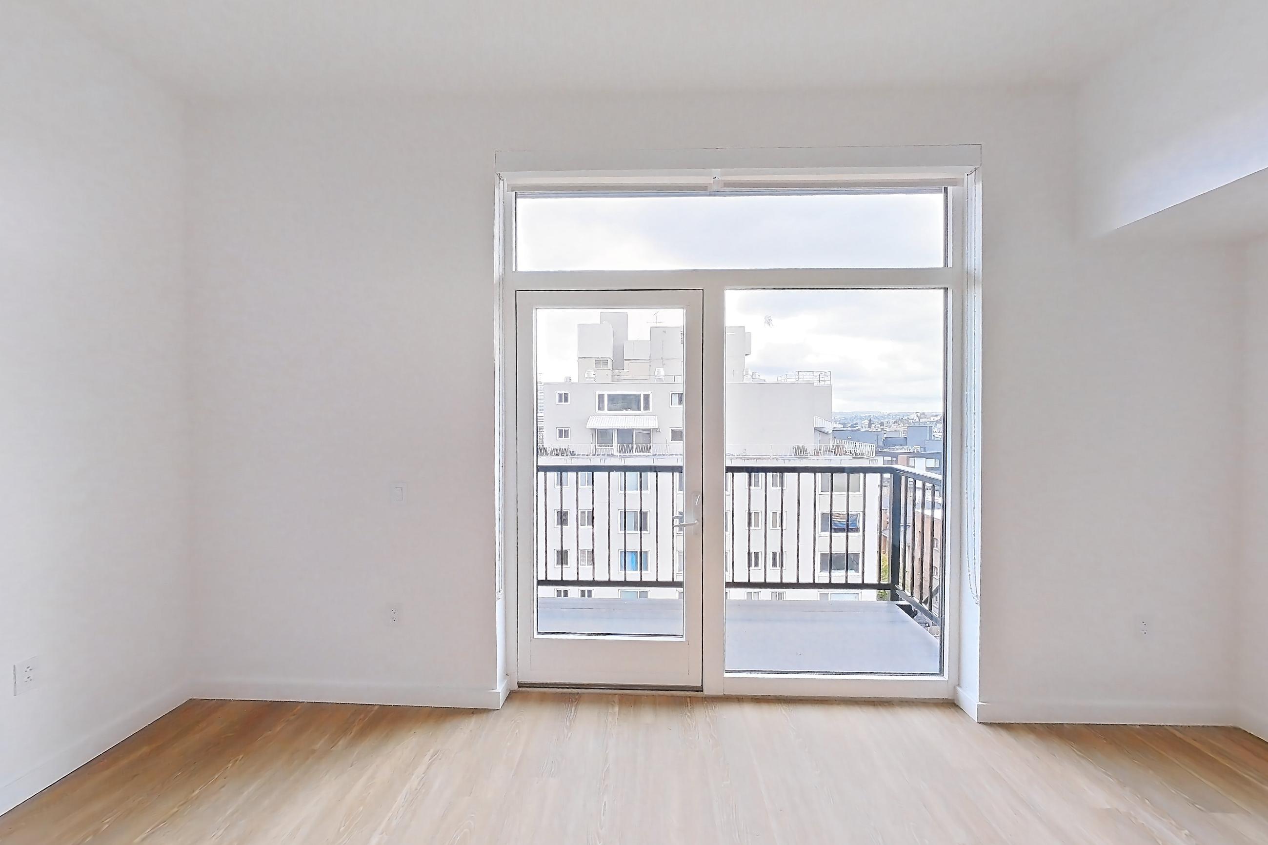 Living room with light wood-finish flooring and mini-split AC, Apartment 804 at The Victor