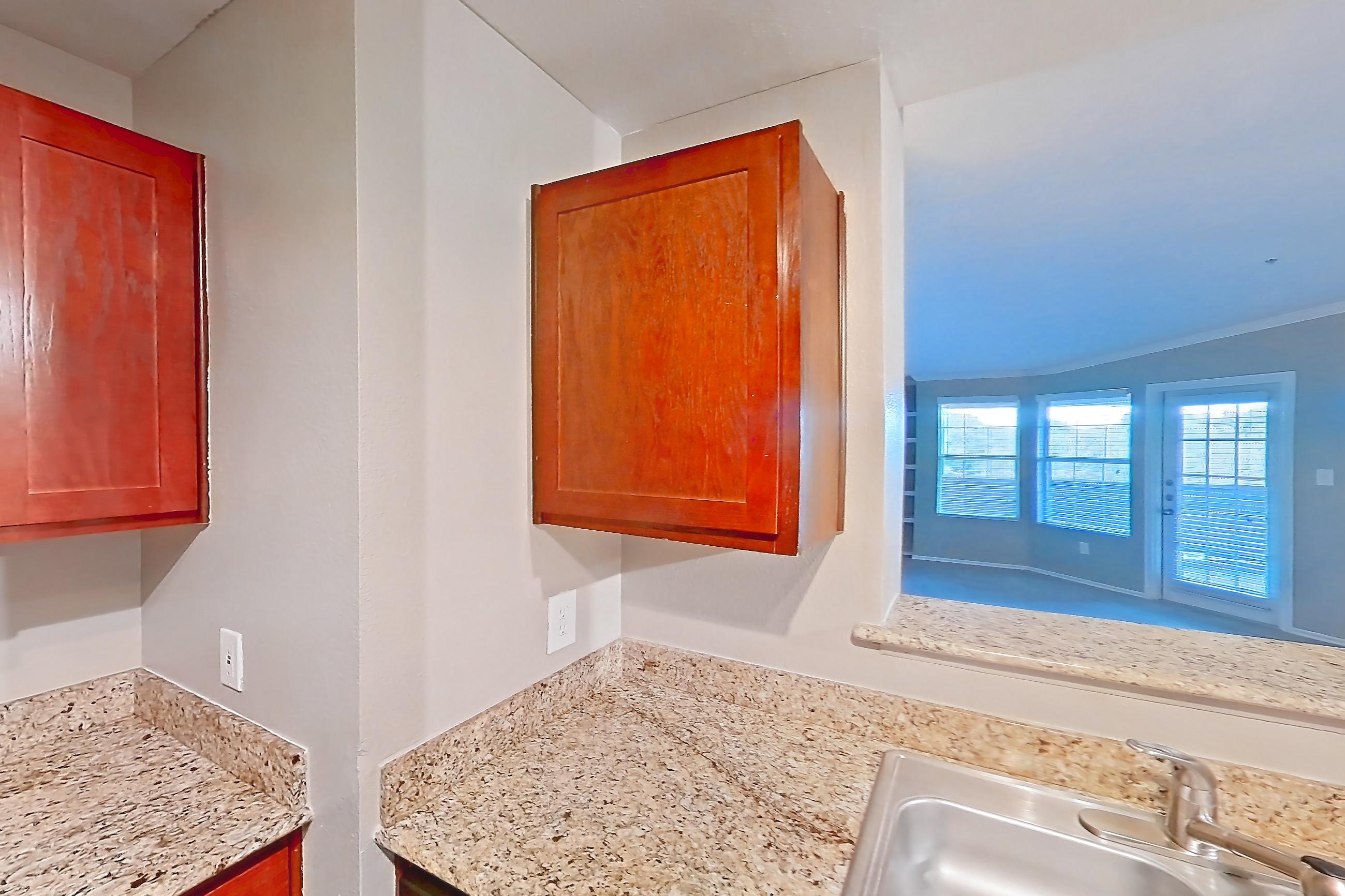 Kitchen with black appliances, dark wood-finish flooring, dishwasher, electric range, light stone countertops, microwave, oven/range, refrigerator, and stainless steel appliances, Apartment 0309 at Marquis at Barton Trails I